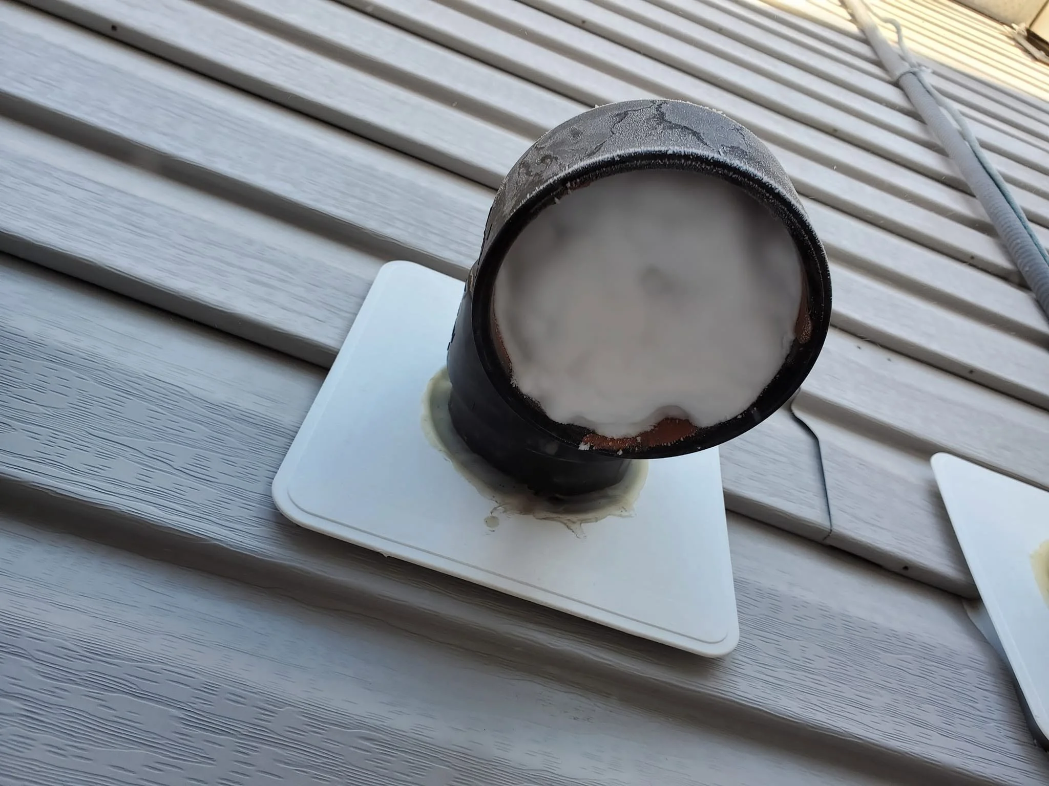 A black cup filled with a foamy beverage, placed on a white square plate on a light gray wooden surface.