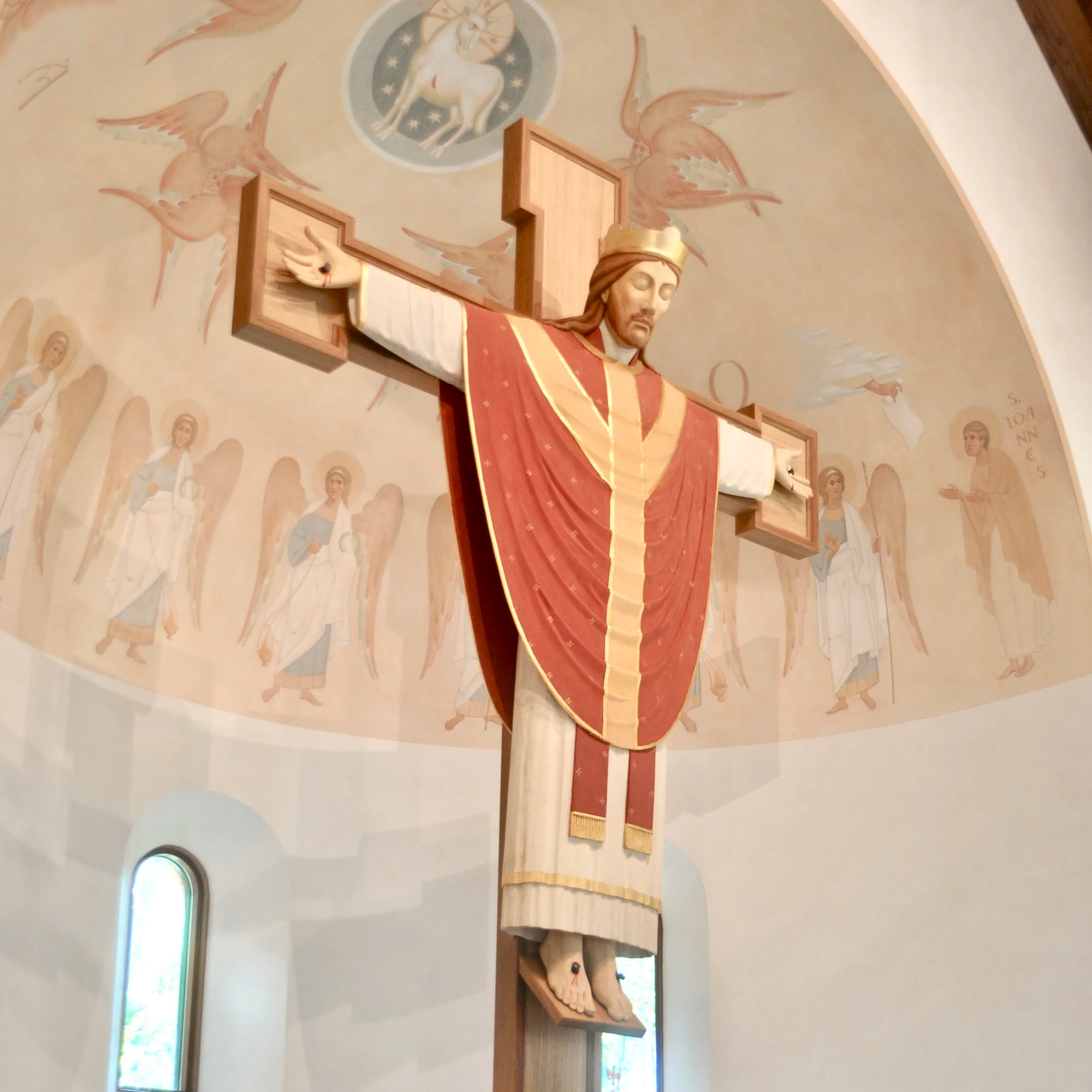 Wooden statue of Jesus Christ on the cross with a painted ceiling featuring a white horse and angelic figures in the background.