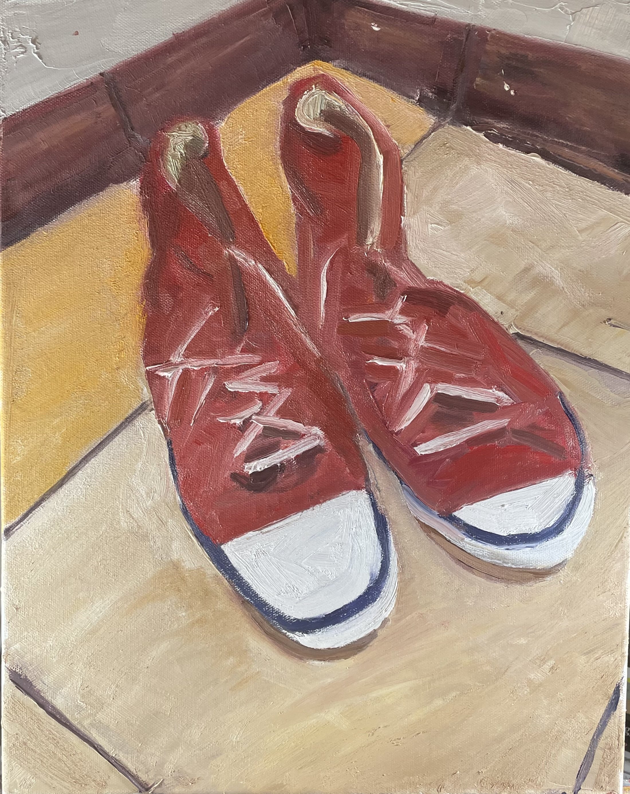 Poets Studio. Close-up of a painting of a red pair of sneakers on a beige surface with yellow and brown background elements. Painting by David Biespiel.