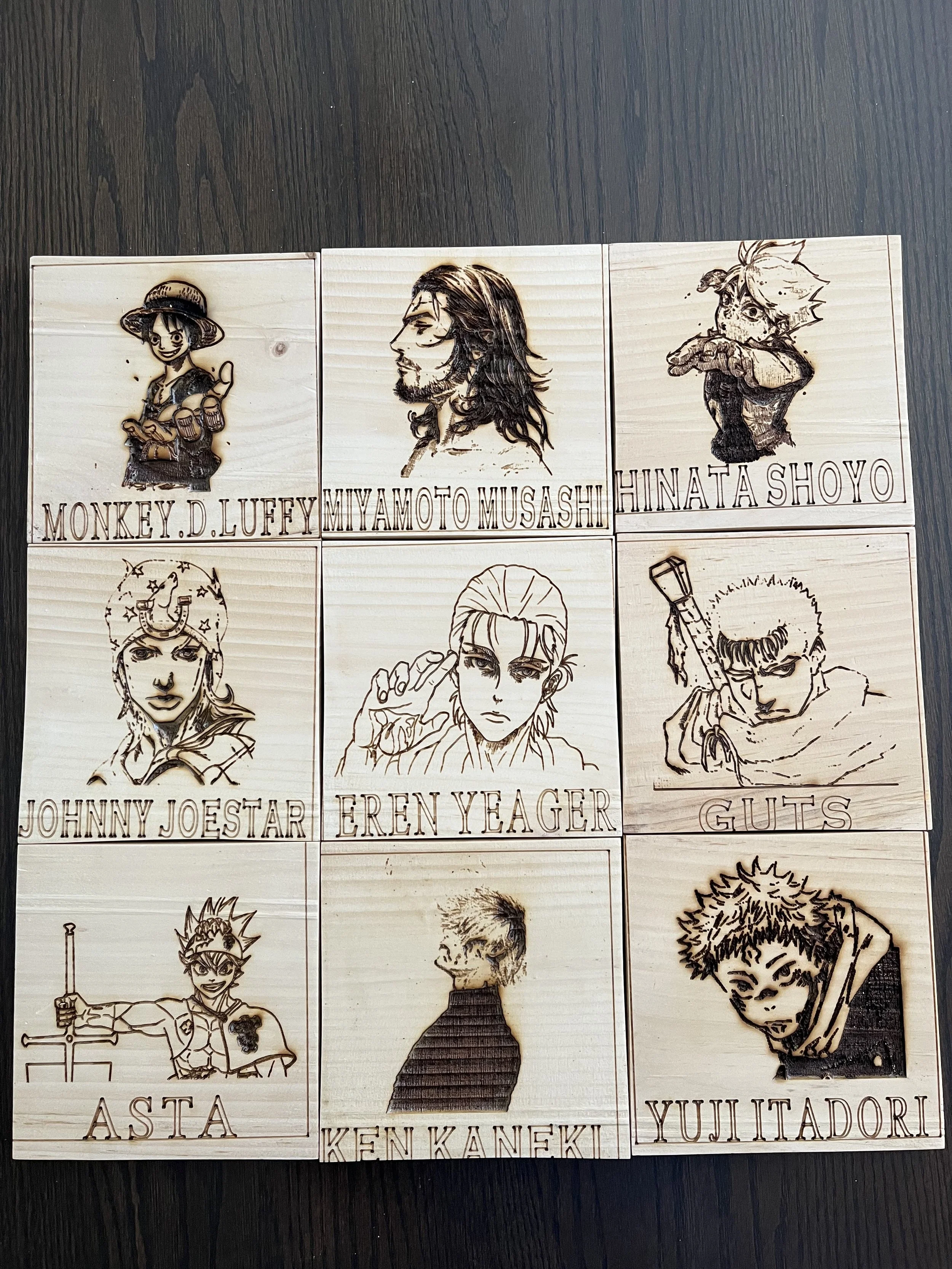 Six wooden plaques with engraved characters and names from popular anime series, including Monkey D. Luffy from 'One Piece', Miyamoto Musashi, Hinata Shoyo from 'Haikyuu!!', Johnny Joestar from 'JoJo's Bizarre Adventure', Eren Yeager from 'Attack on 