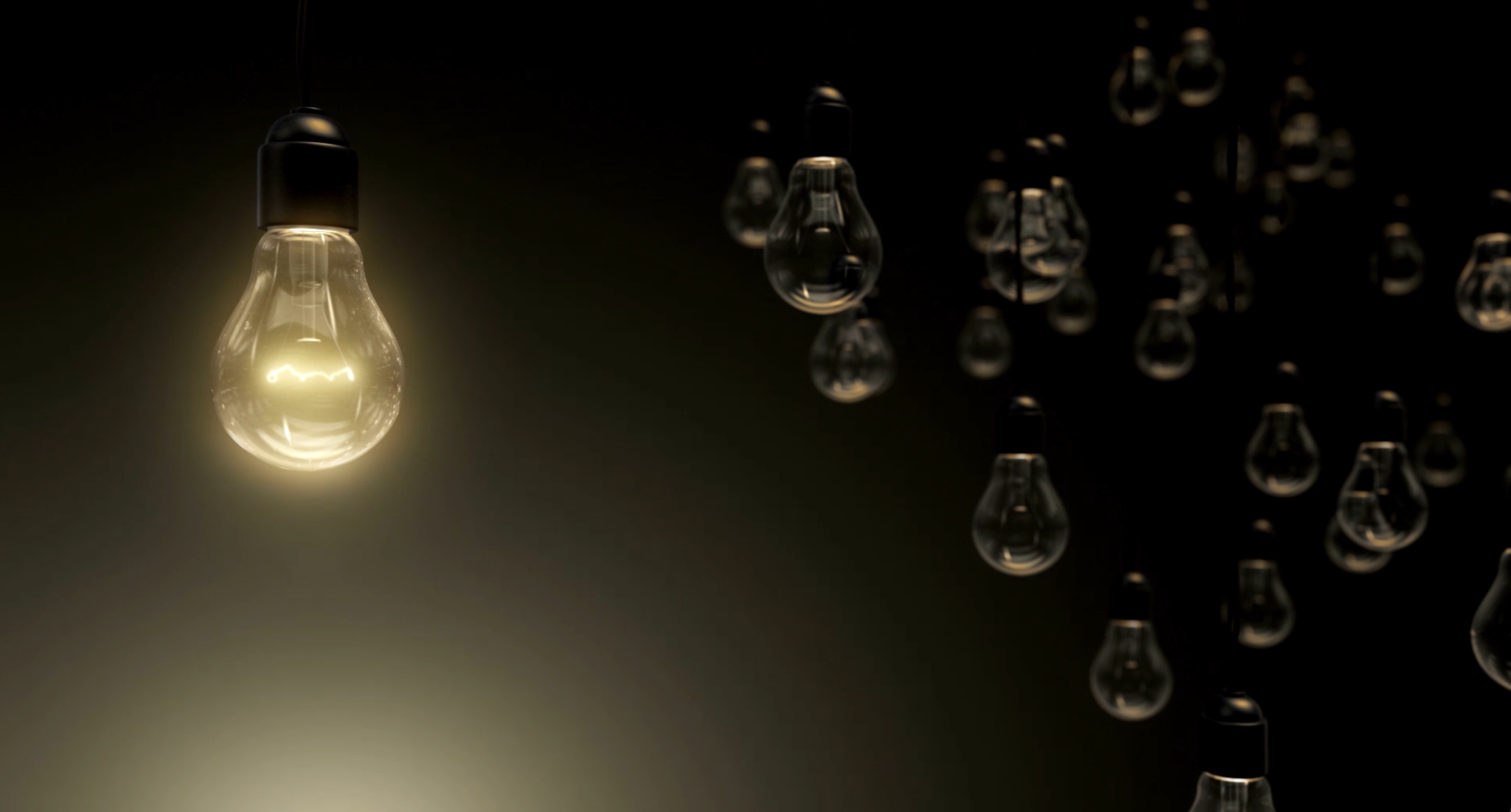 Multiple hanging light bulbs with one illuminated bulb in the foreground against a dark background.
