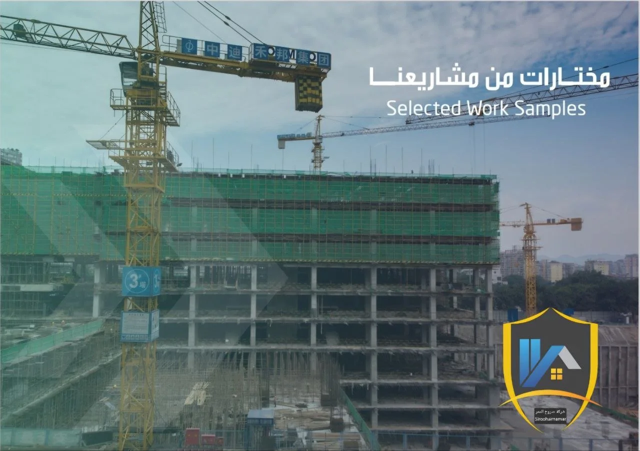 Construction site with multiple cranes and a partially built multi-story building covered in green safety netting, under a cloudy sky.