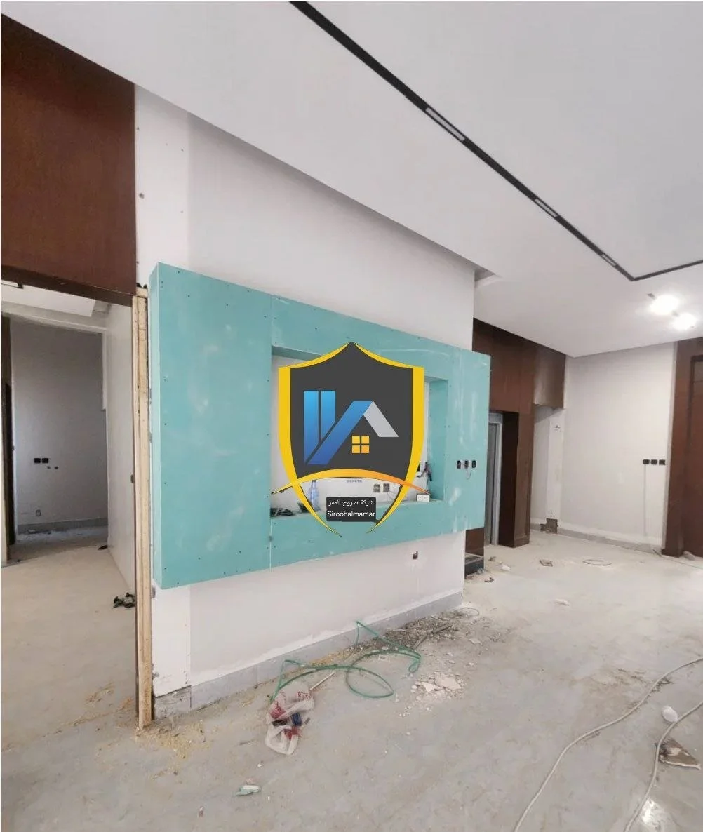 Interior of a construction site with unfinished walls and ceiling, scattered debris, and electrical wiring, indicating ongoing renovation or building work.
