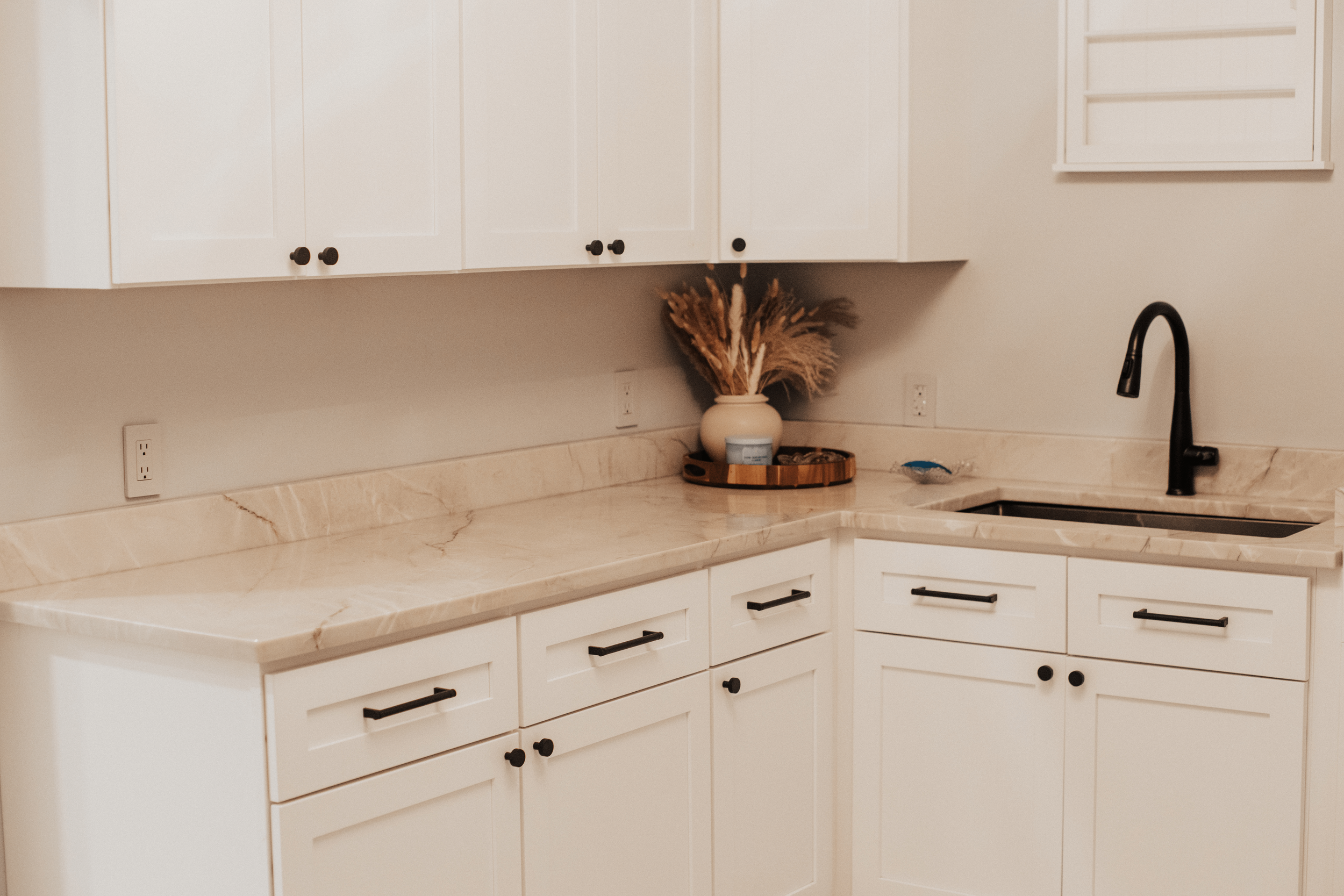 a delaware kitchen with a textured countertop, white cabinets, sink, and plant decorations
