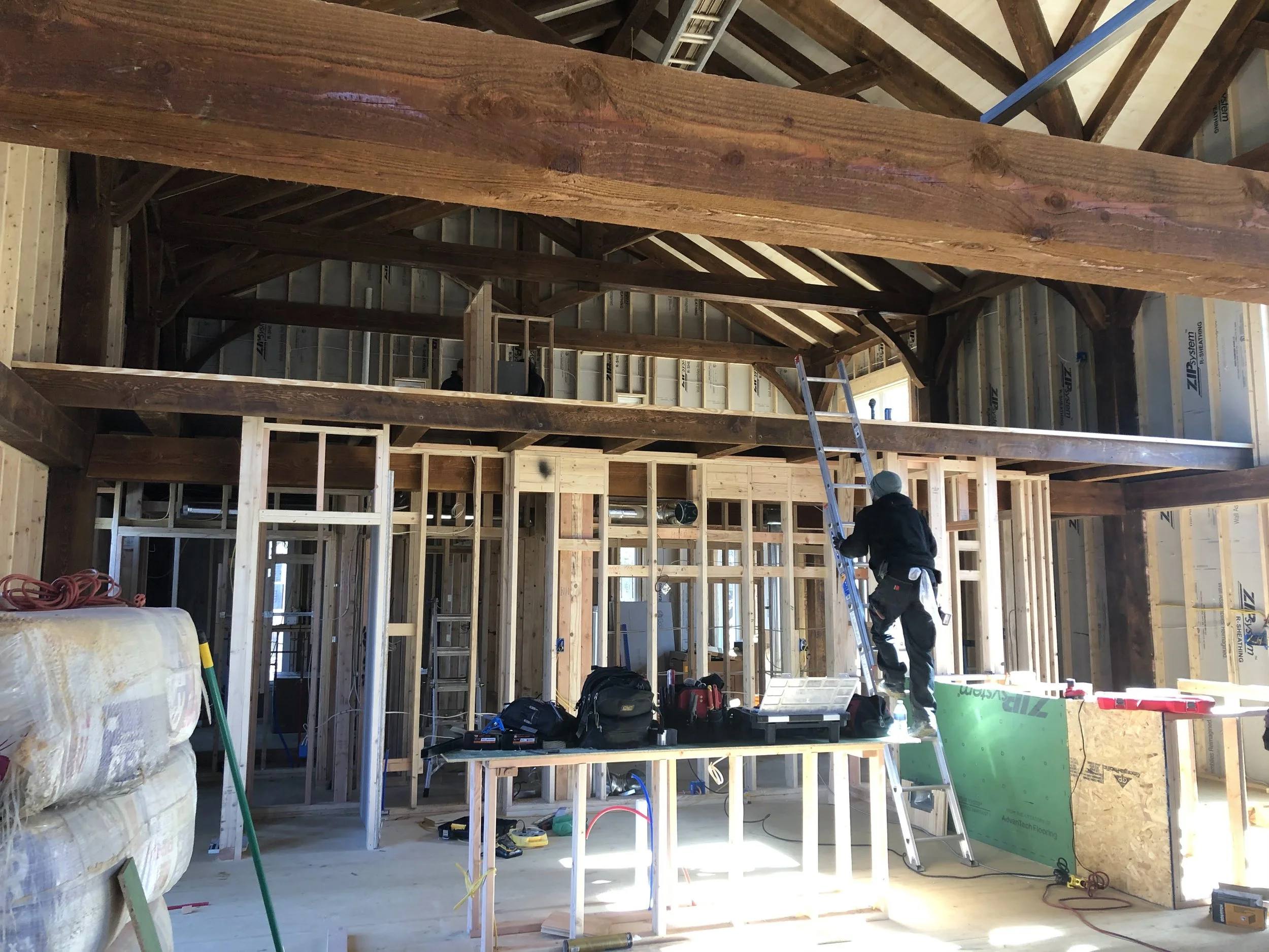 Interior of a post and beam building under construction showing wooden framing, and a loft space.