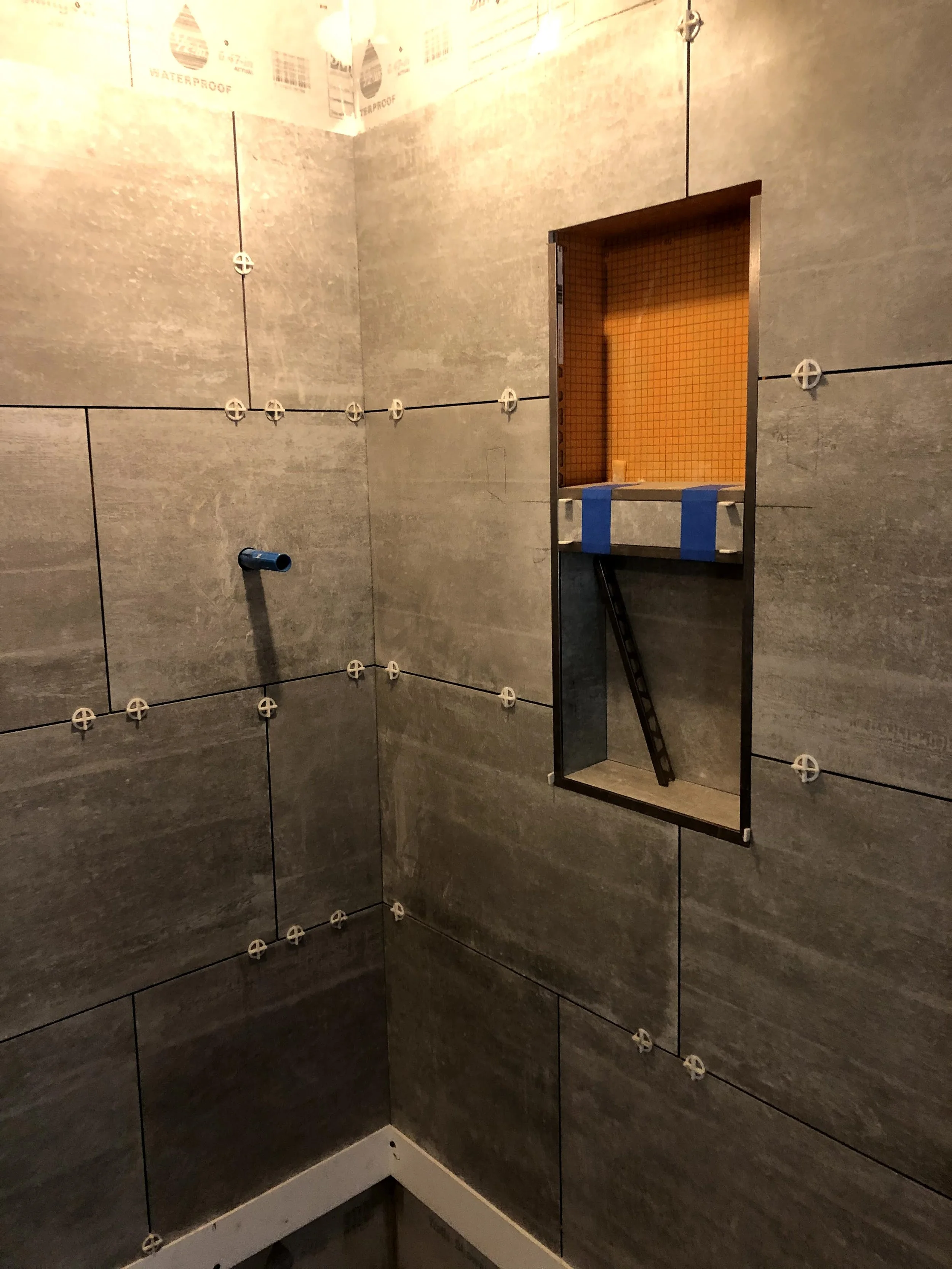 Interior of a bathroom shower with gray tile walls under construction.