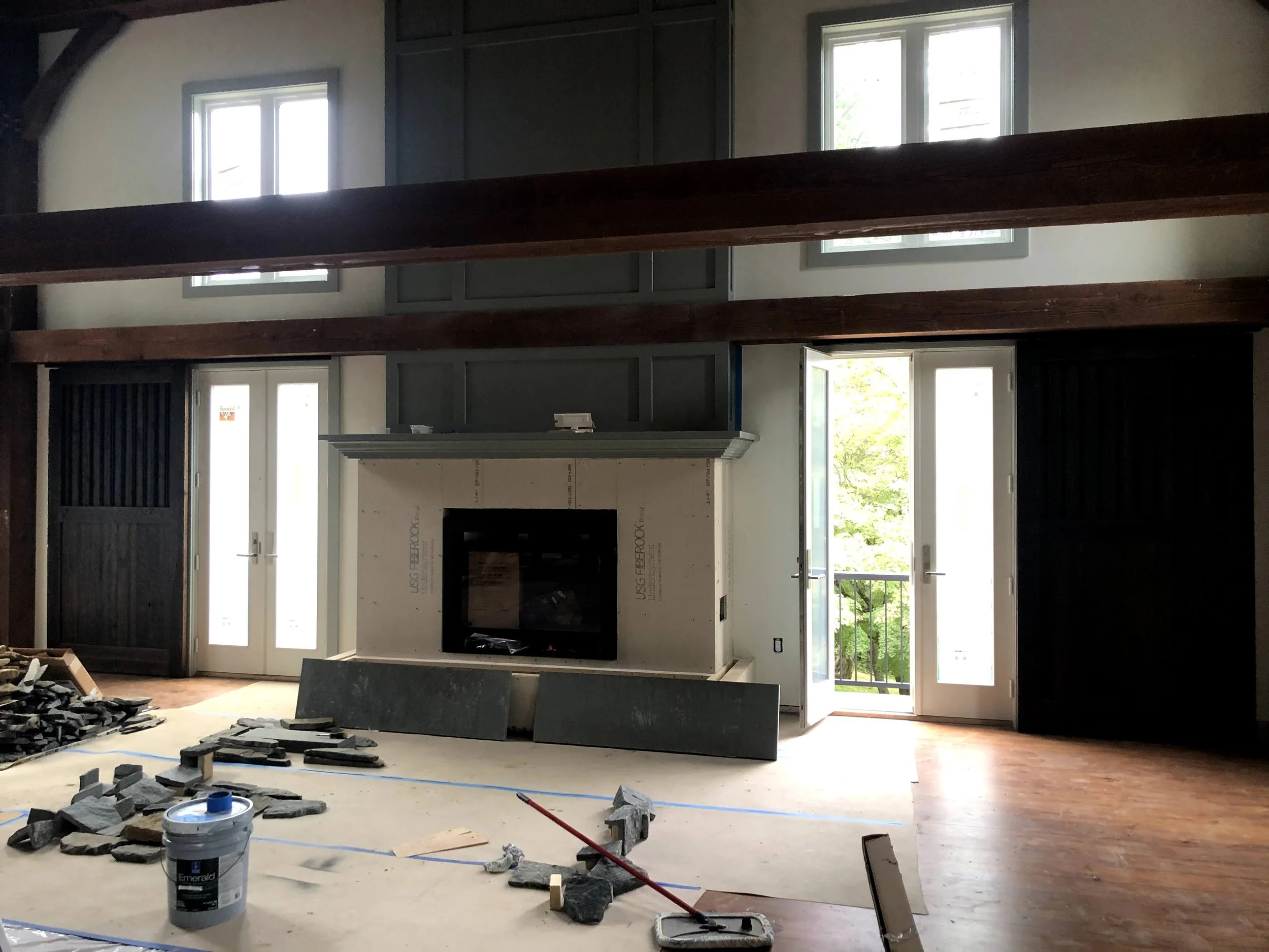Great room under construction with a fireplace, clerestory windows, and balcony doors.