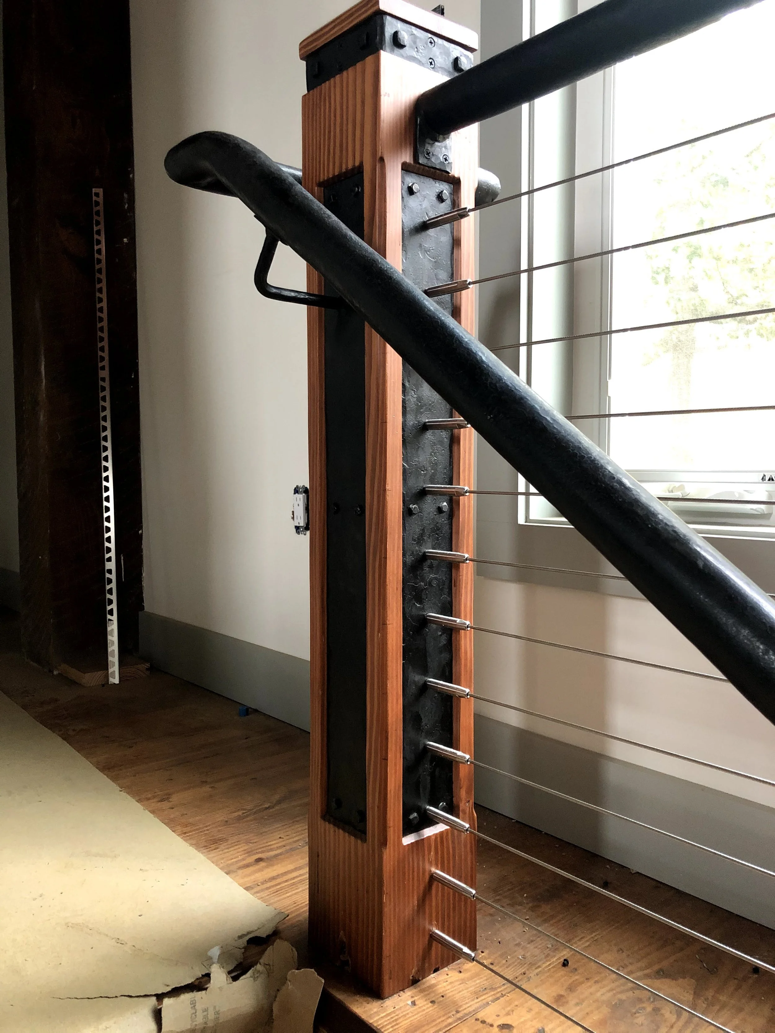 Close-up of a wooden and metal tensioned wire structure, possibly part of a climbing or workout apparatus, situated indoors near a window.
