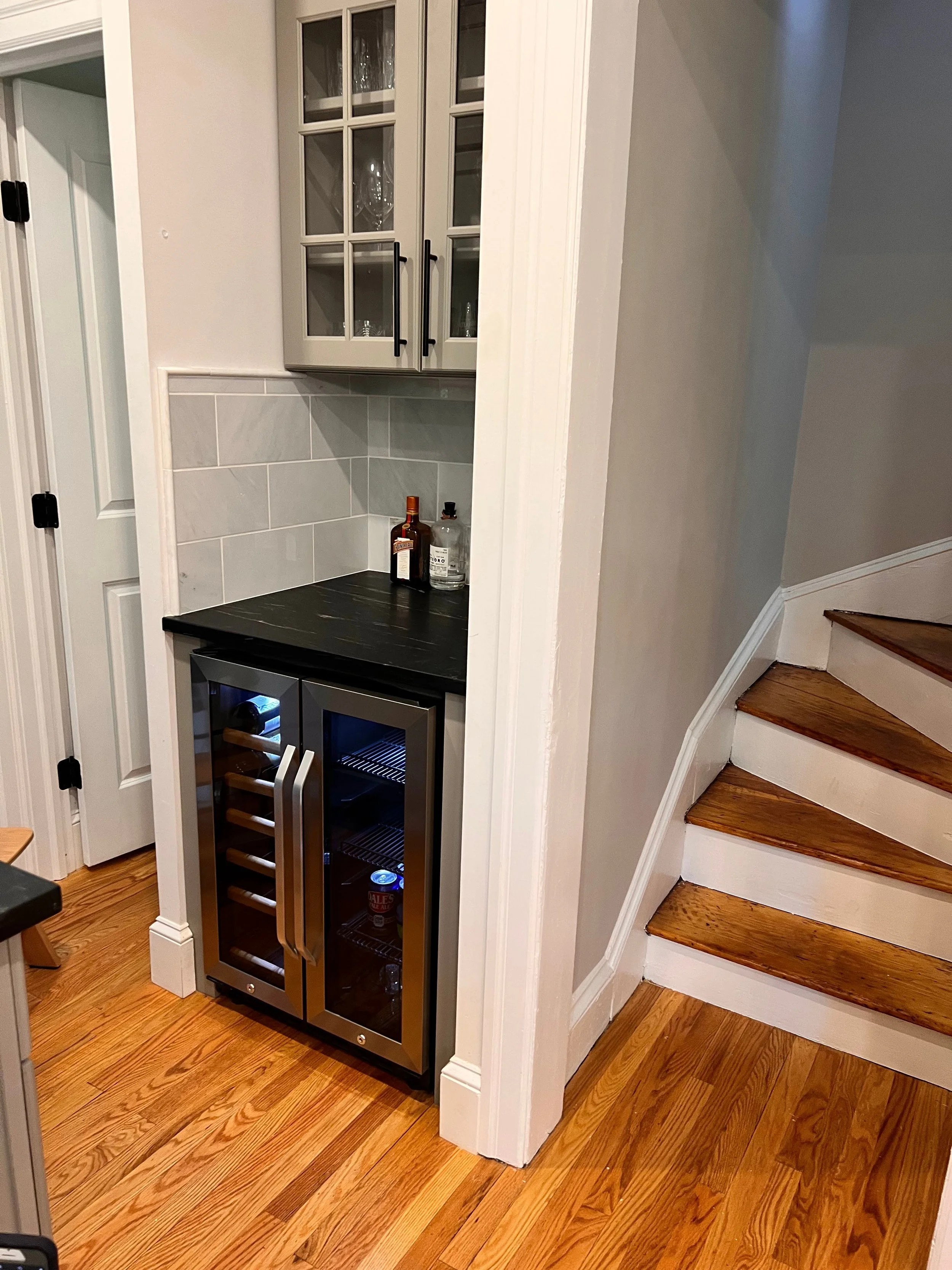 Home bar area with wine cooler, glass cabinet, countertop, and stairs