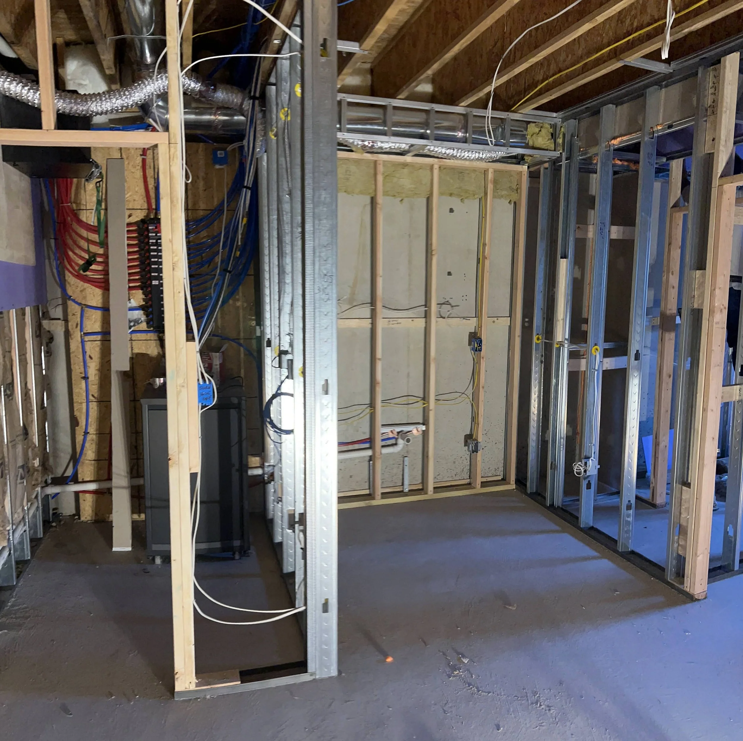 Interior of a building under construction showing metal framing, electrical wiring, and drywall.
