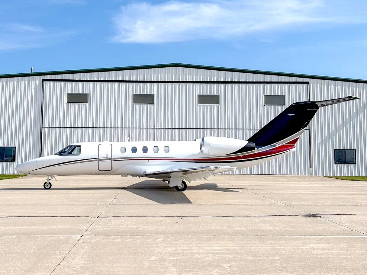 Private jet parked on tarmac in front of a hangar.