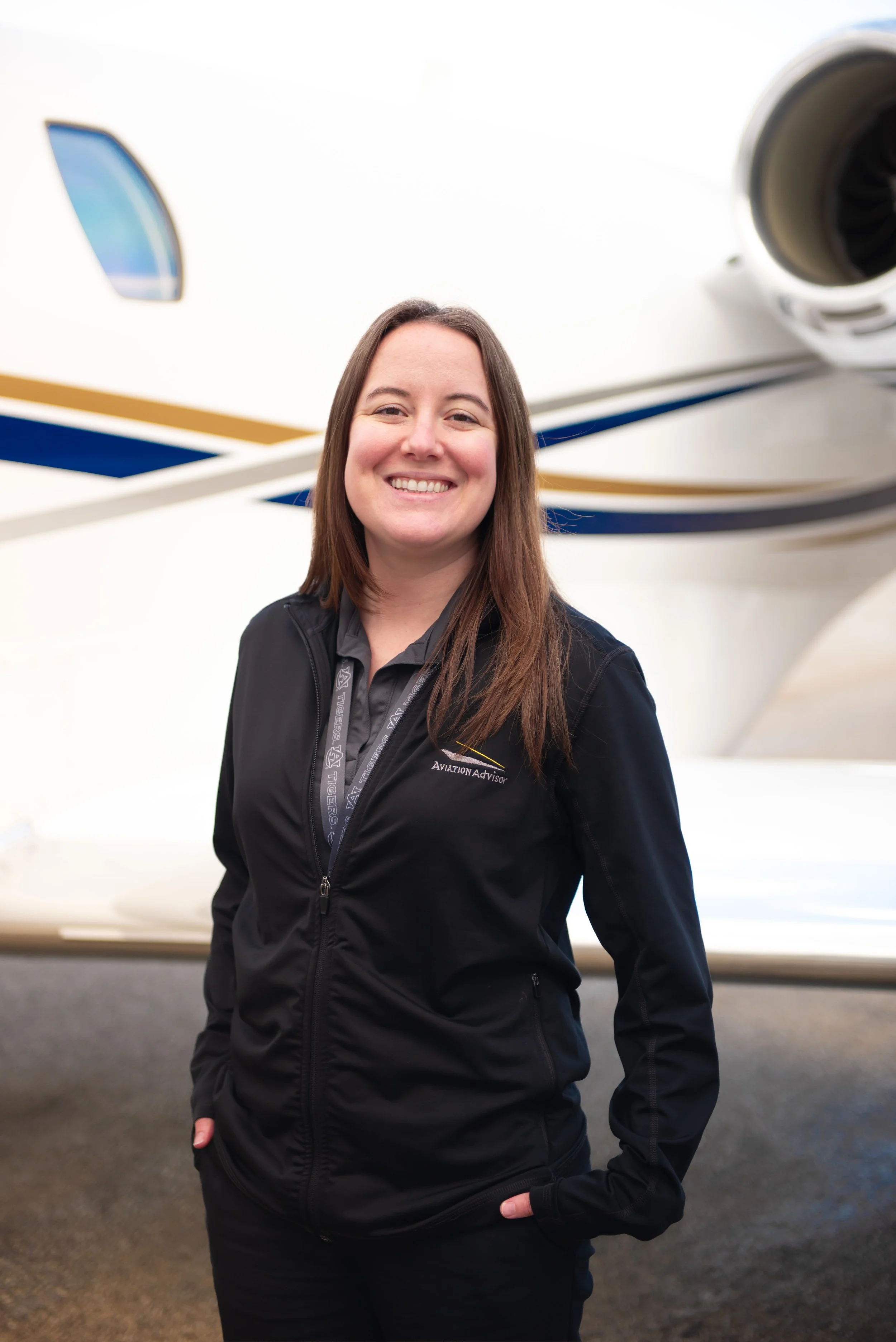 smiling woman standing in front of a private jet