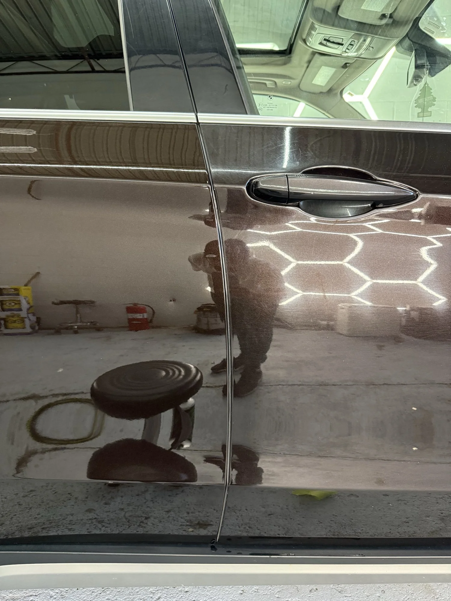 50/50 paint-correction comparison on brown BMW doors under inspection lights