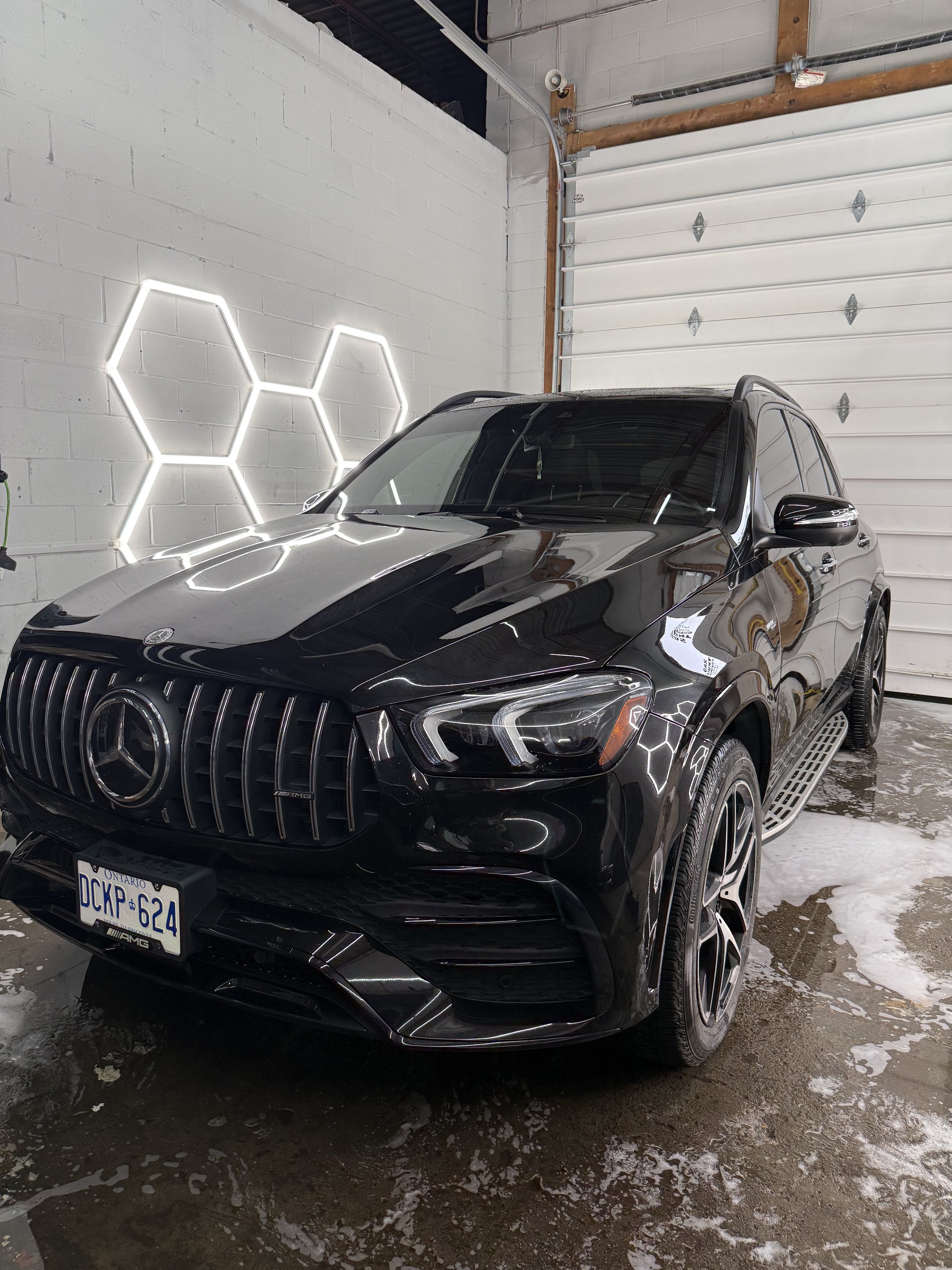 Black Mercedes-AMG SUV under hex lights inside the detailing studio