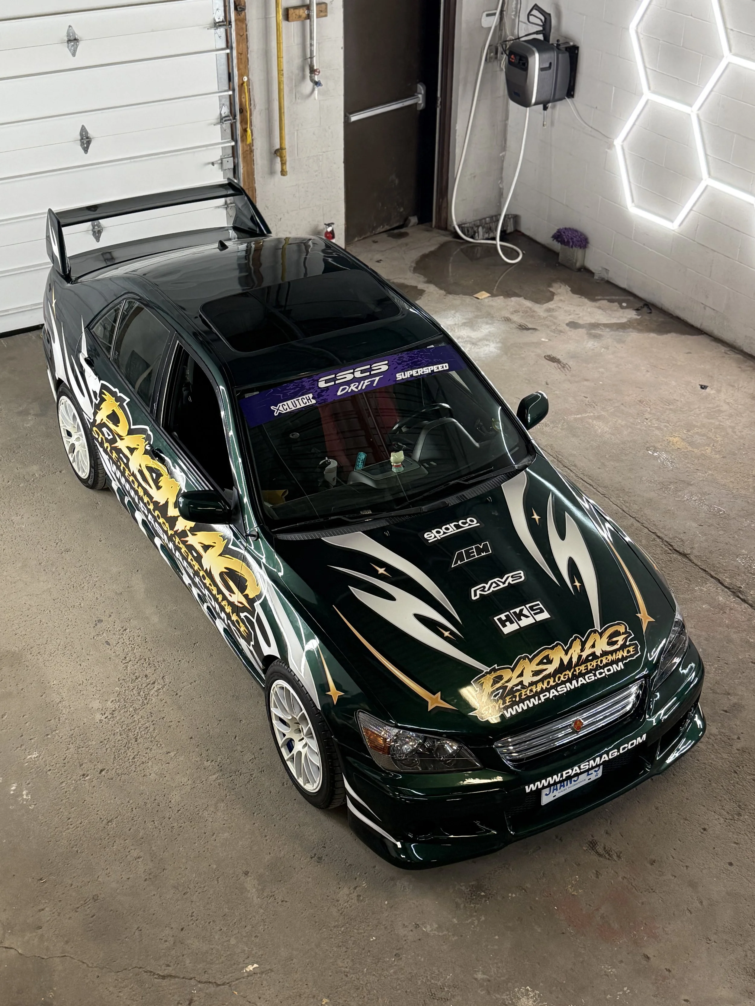 Green drift car with PASMAG racing livery inside the studio
