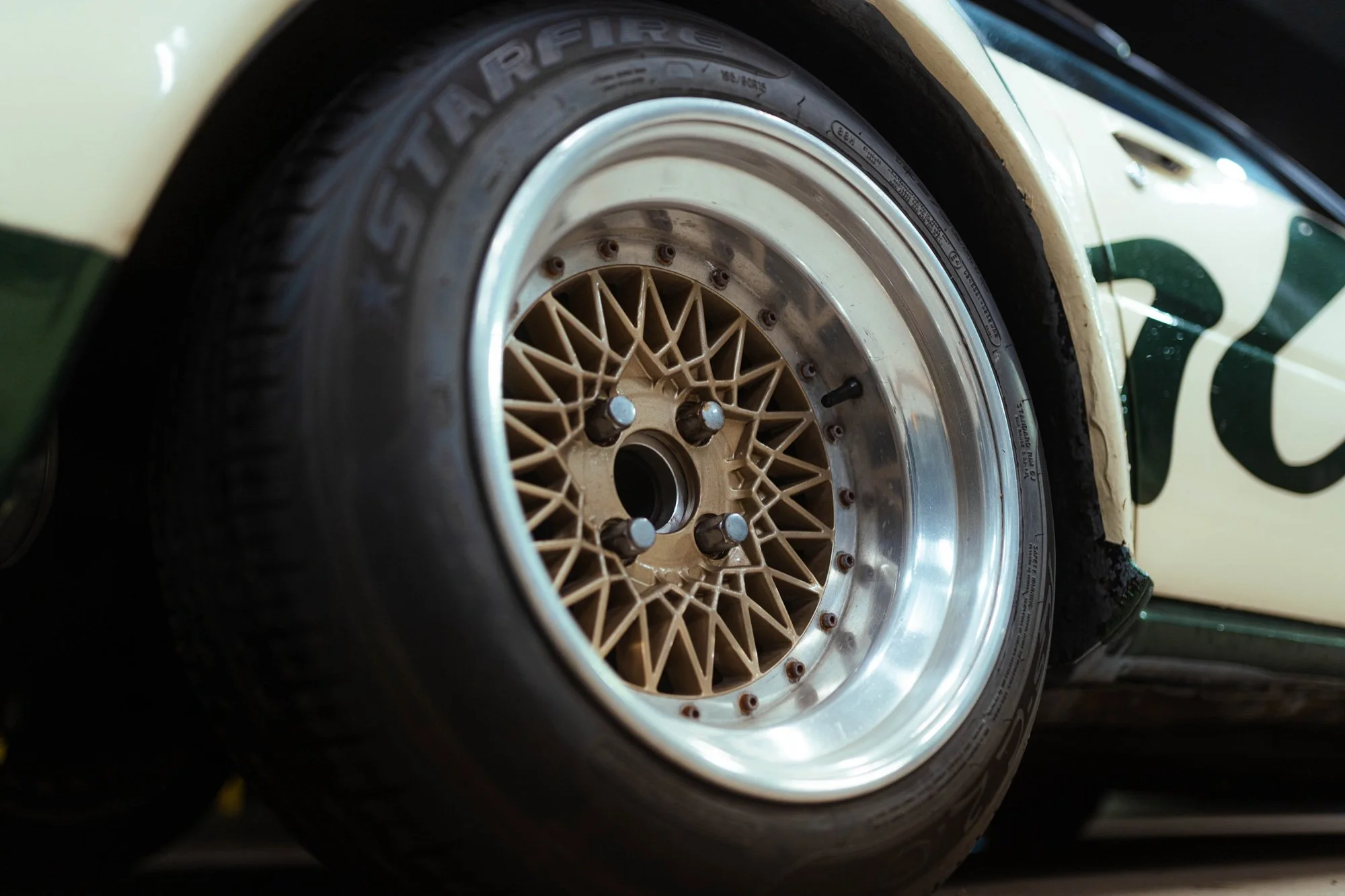 Gold mesh wheel and polished rim on a white and green project car