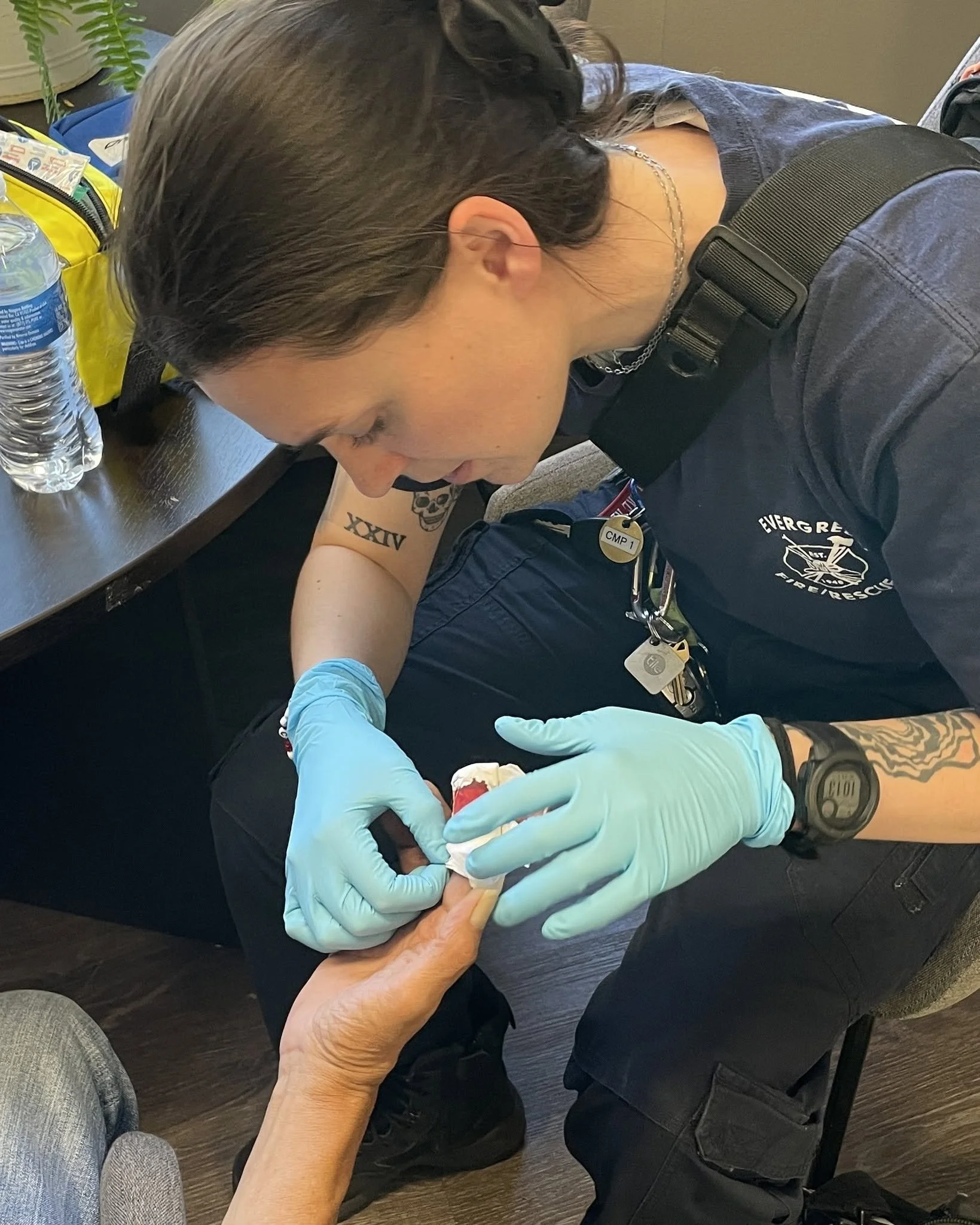 A person administering a shot or vaccination to another person's arm, wearing gloves, in an indoor setting.