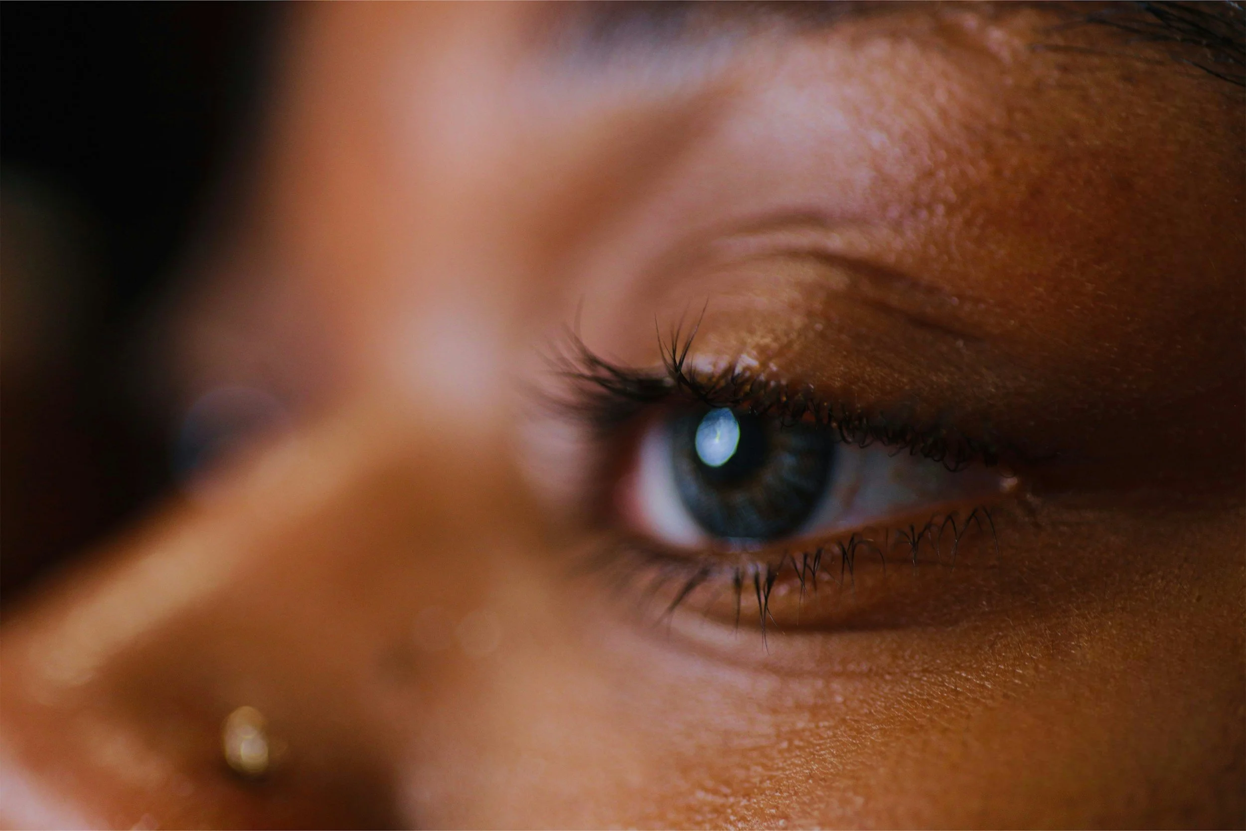Close-up of a person's eye and brow, with focus on the eyelashes and eye iris.