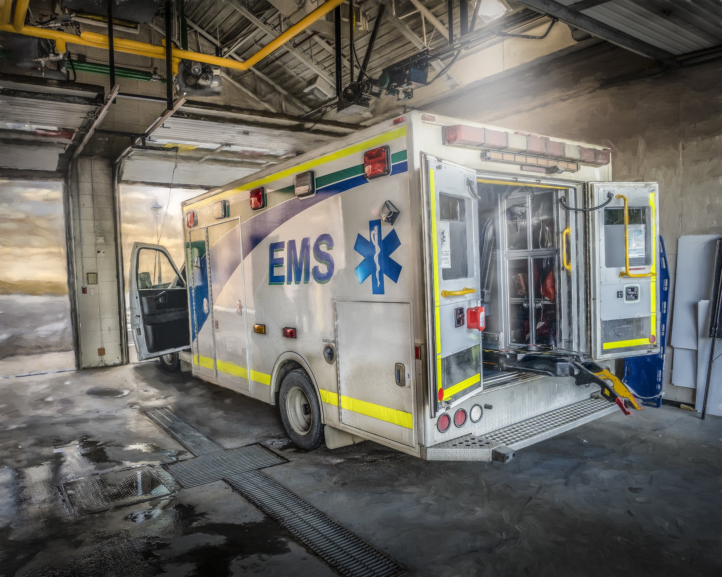 An ambulance inside a washing bay washing its exterior with soap and water.