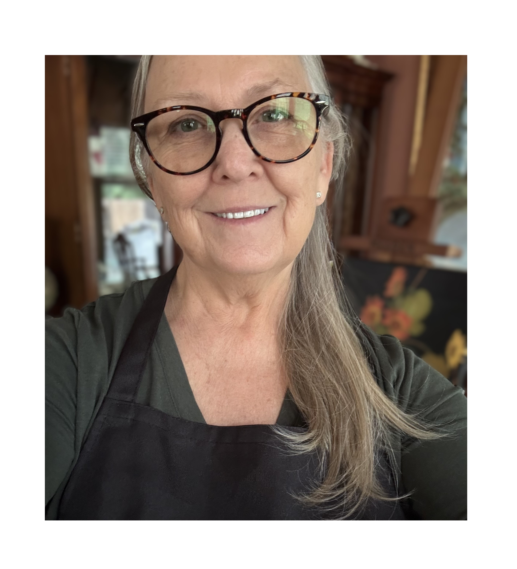 Close-up of a smiling woman, the artist, Theresa Parsons, with glasses and long blonde hair, in her art studio.