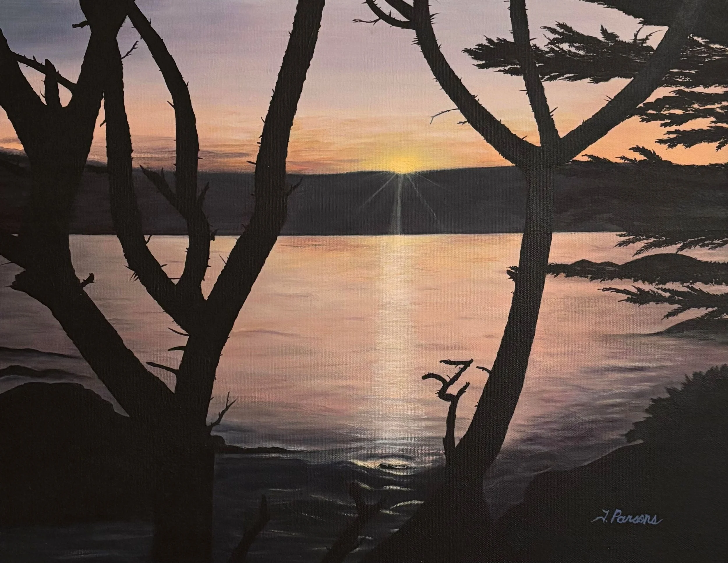 Silhouetted trees by a body of water during sunset with a pink and orange sky and visible sun rays.