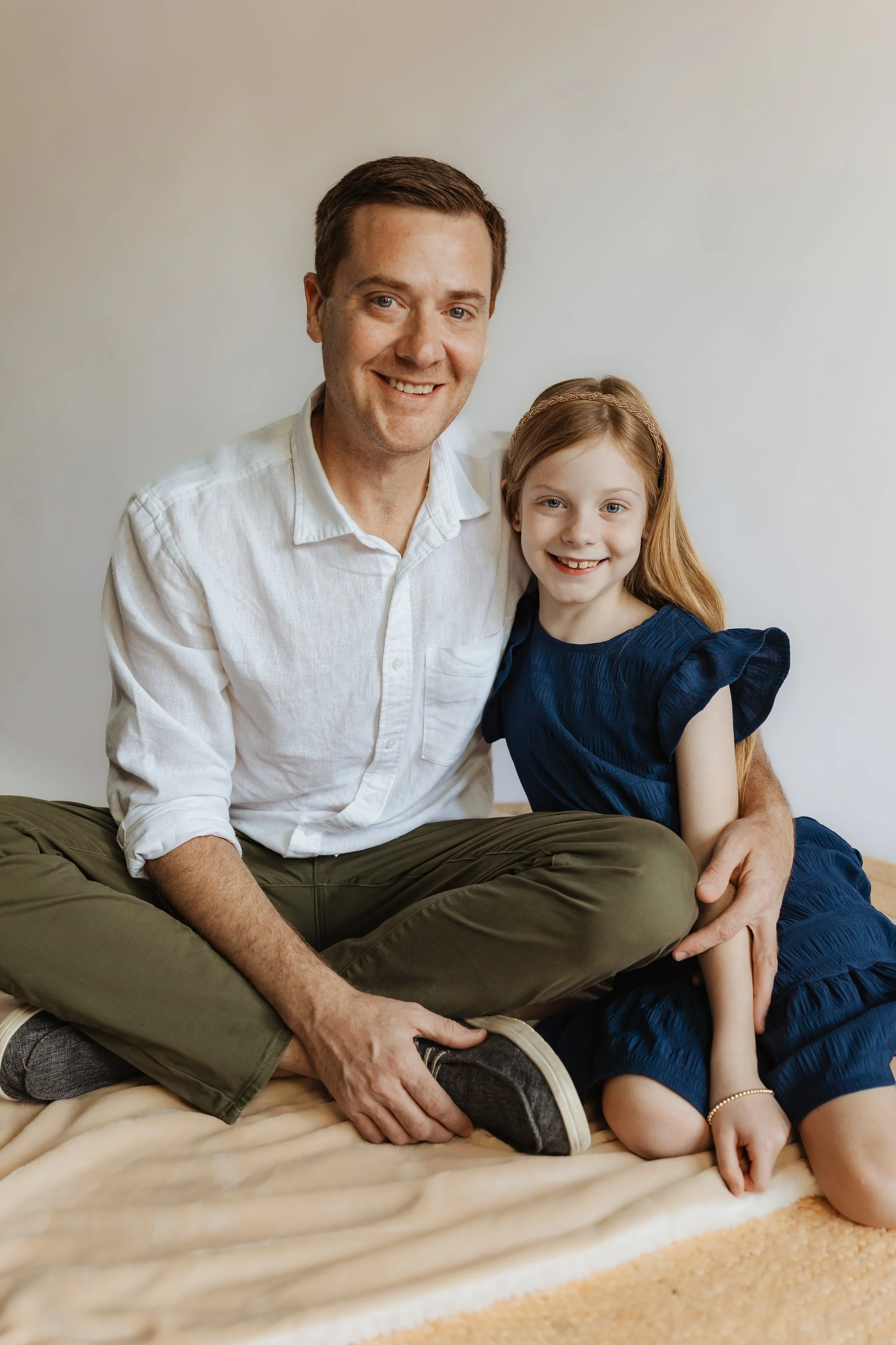 Mike Falco is sitting on a blanket with his smiling daughter