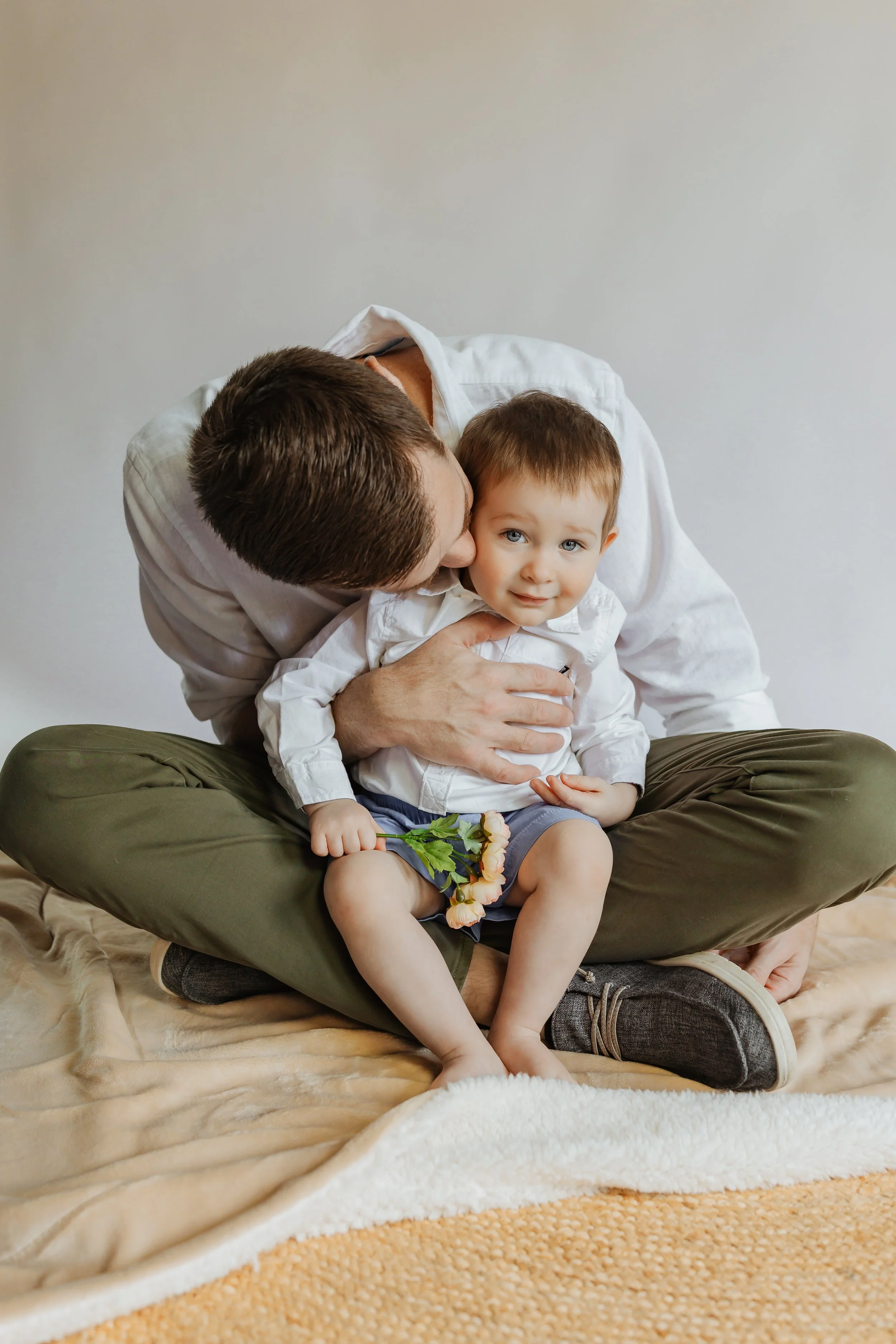 Mike Falco is kissing his toddler son, who sits in his lap
