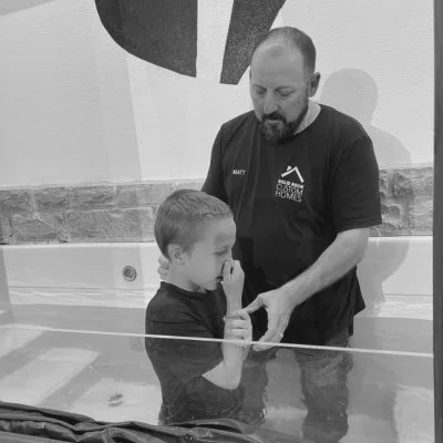 A man baptizing a young boy in a body of water.