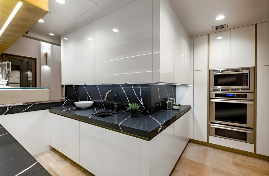 Modern kitchen with black marble countertops, white cabinets, and built-in stainless steel microwave and oven.