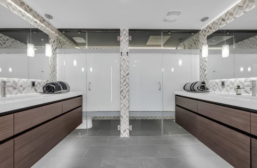 Modern public restroom with double vanity sinks, large mirrors, and glass stall doors.