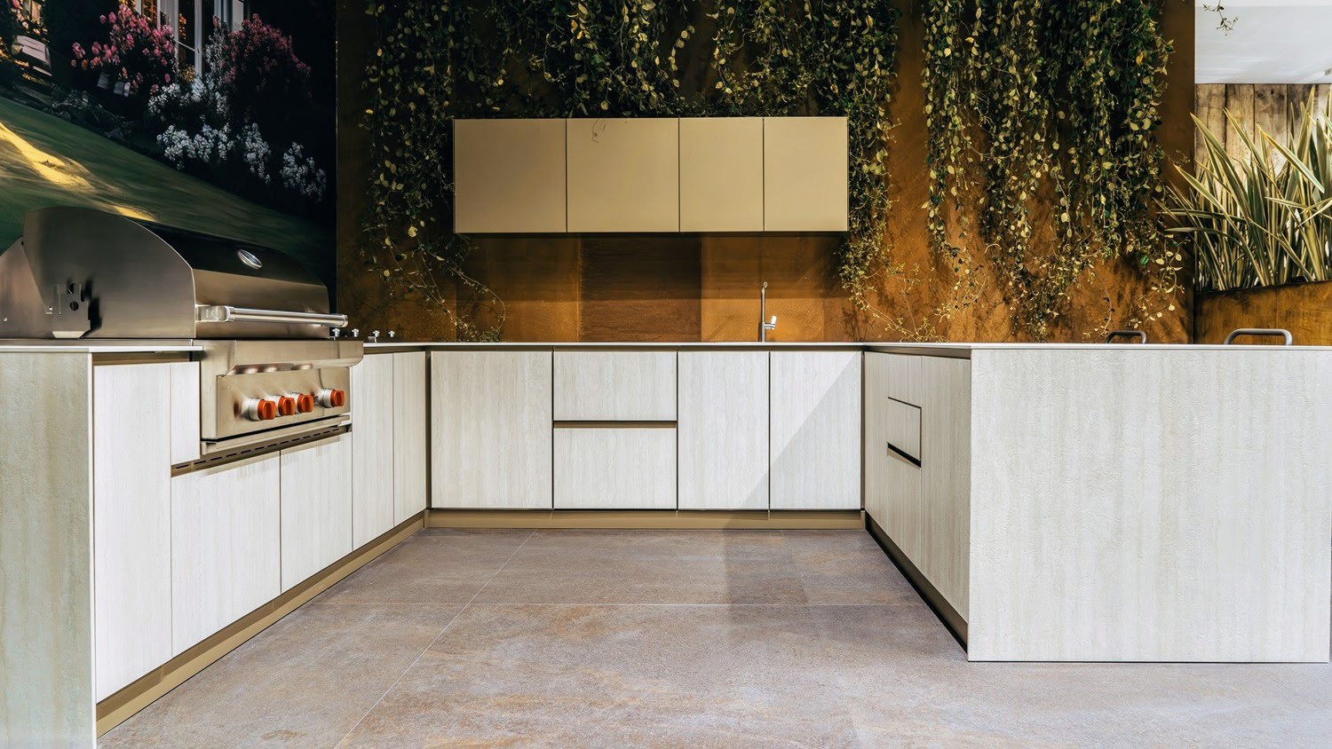 Outdoor kitchen with white cabinetry, stainless steel grill, sink, and greenery background