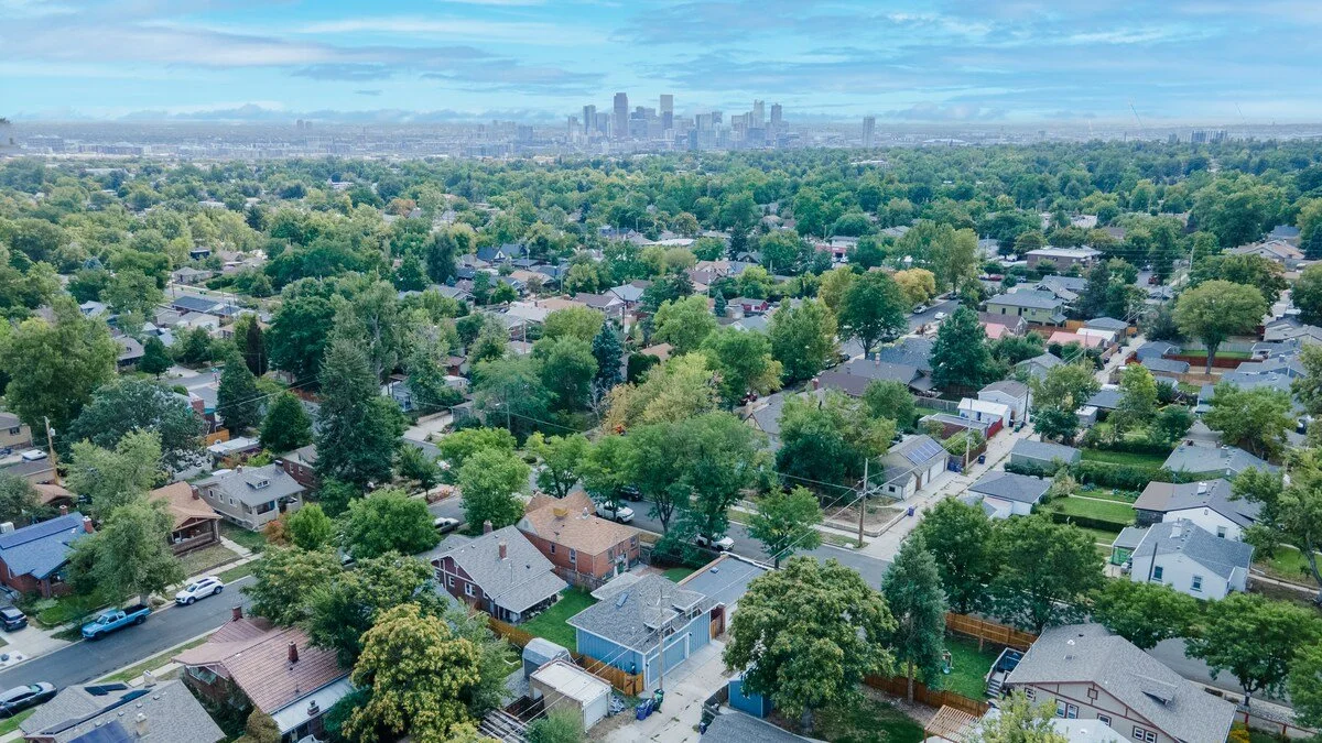 Aerial view of Denver's tree-lined Sunnyside neighborhood with the downtown Denver skyline in the distance