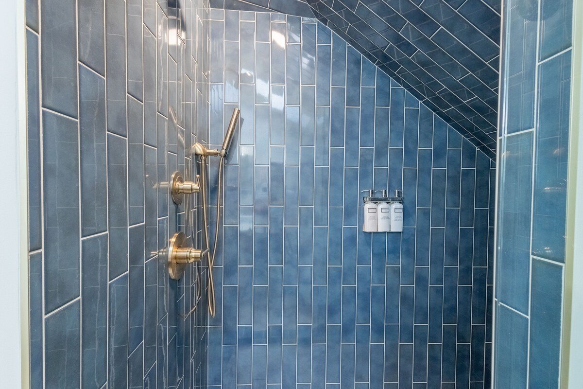 Spa-style walk-in shower with blue tile, strong water pressure, and shampoo, conditioner, and body wash provided