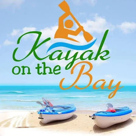 Logo for Kayak on the Bay featuring a kayak, water, and boats on a beach