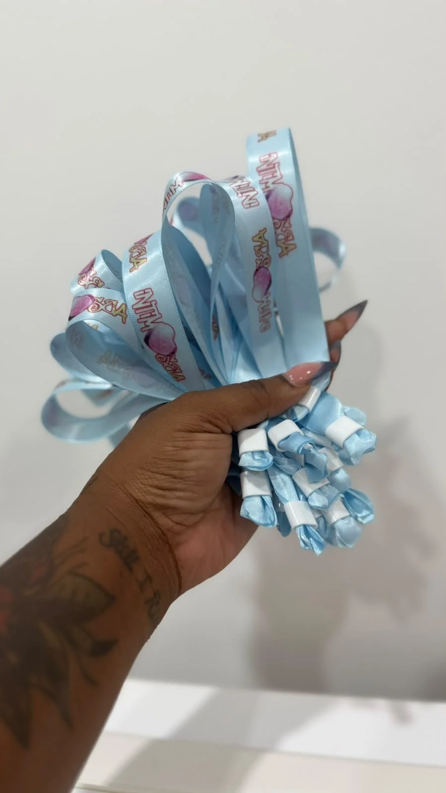 A person holding a blue ribbon with pink hearts and the words "Wedding Vows" printed on it.