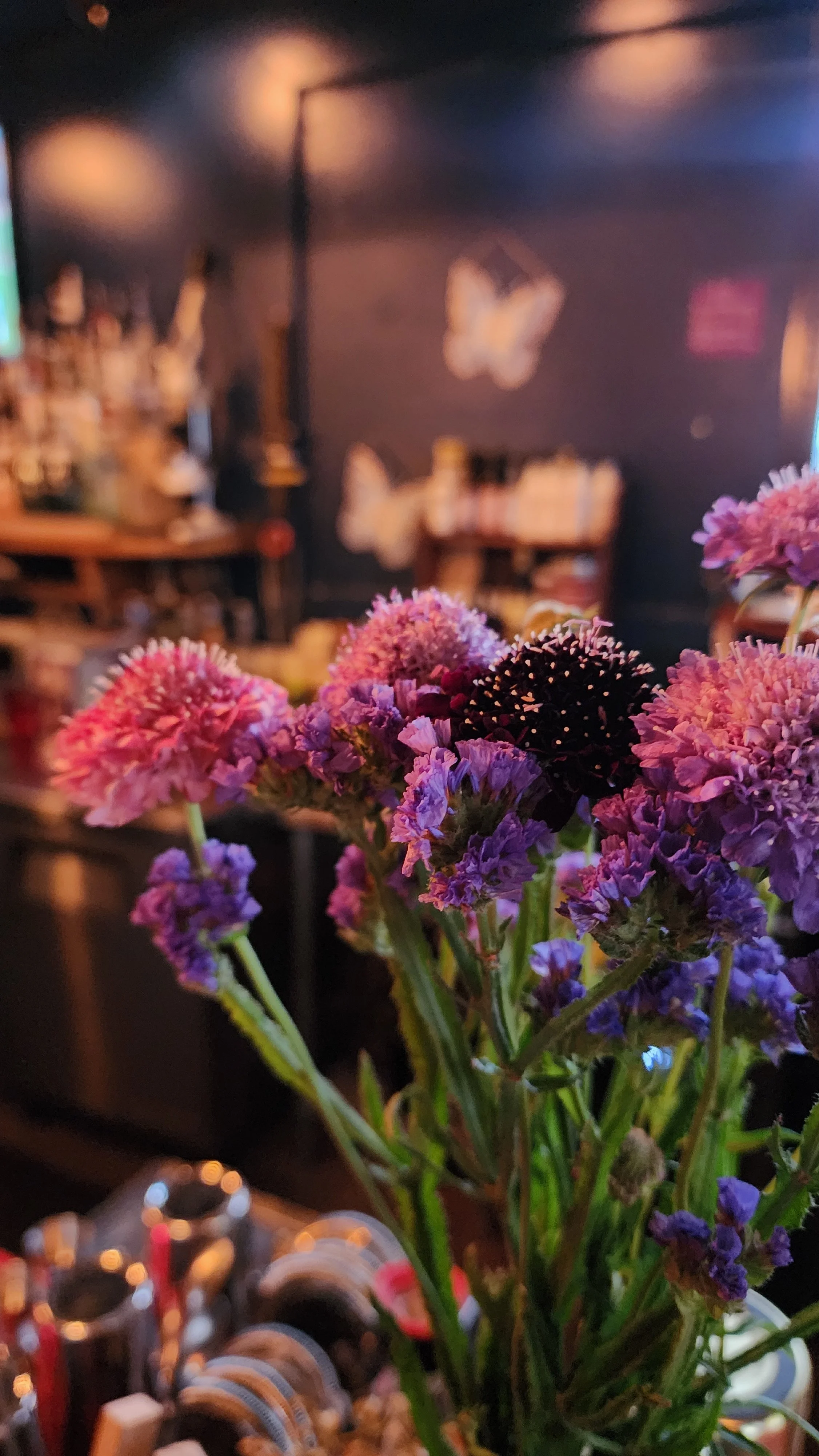 Close-up of a bouquet of purple and pink flowers in a vase on a table.