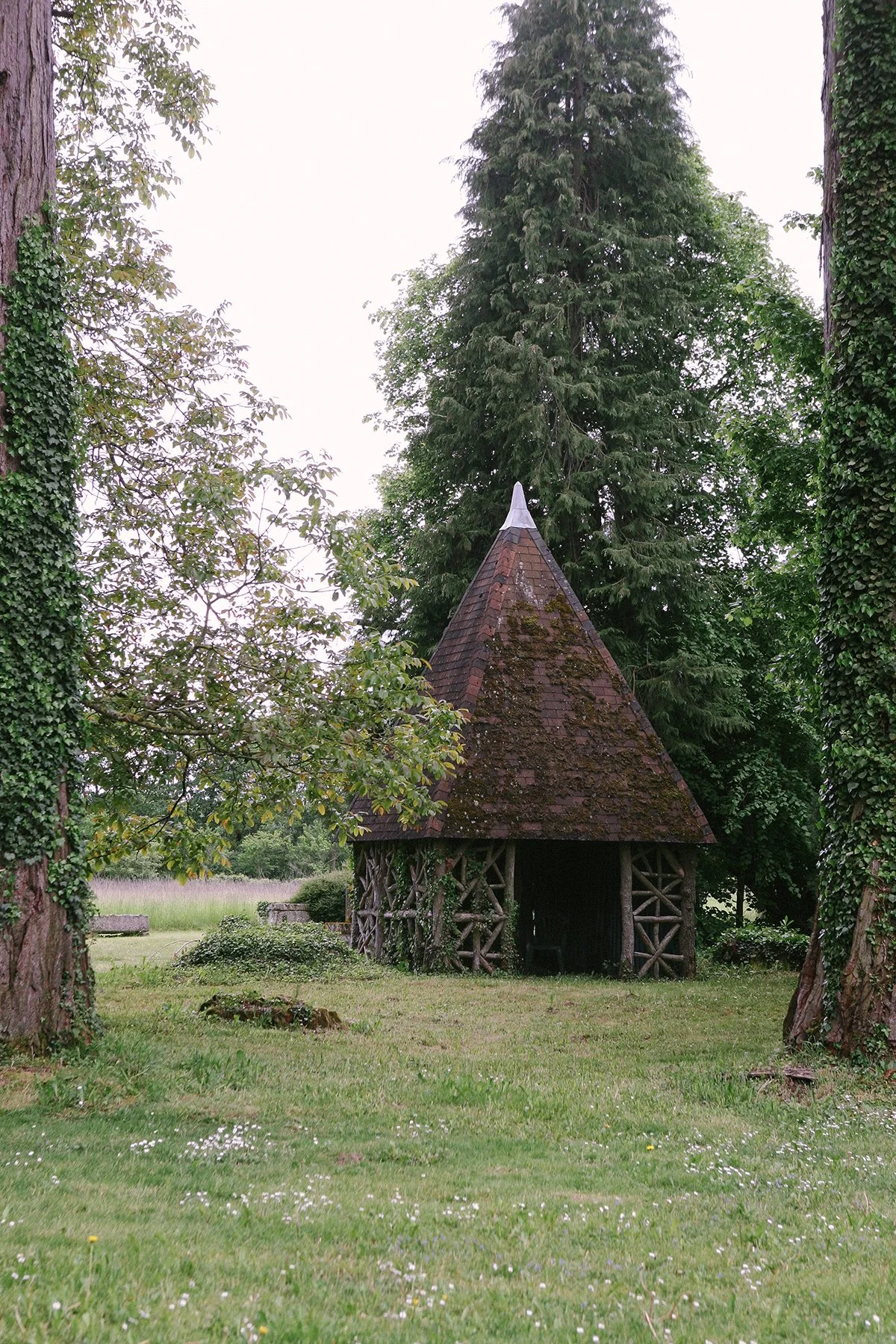 Landscape / Garden design photo of an historic outbuilding made of tree branches and wooden roof tiles on the grounds of Chateau St. Julien, France