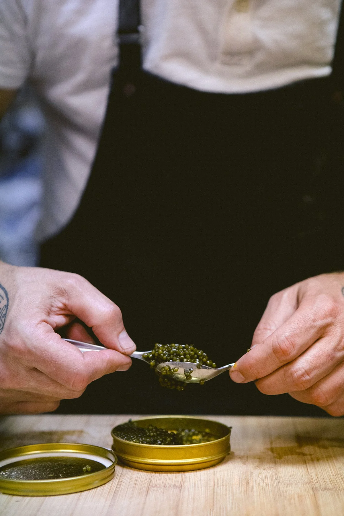 chef in white shirt and black apron makes a Ossetra (Osetra) sturgeon caviar bump.