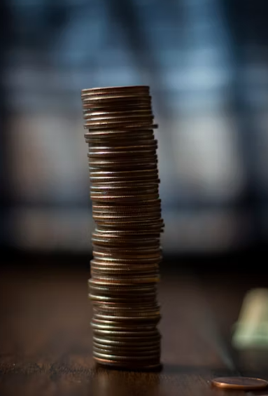 Stack of coins on a wooden surface with a blurred background.