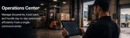 Person using a tablet at an operations center with multiple monitors and a view of trucks outside