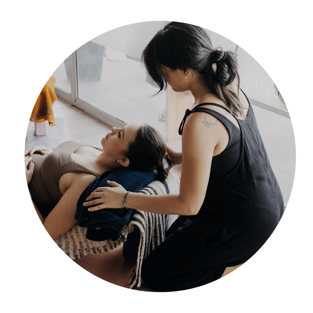 Ale, a birth doula, supporting an expecting mother during a prenatal yoga class in Montreal.