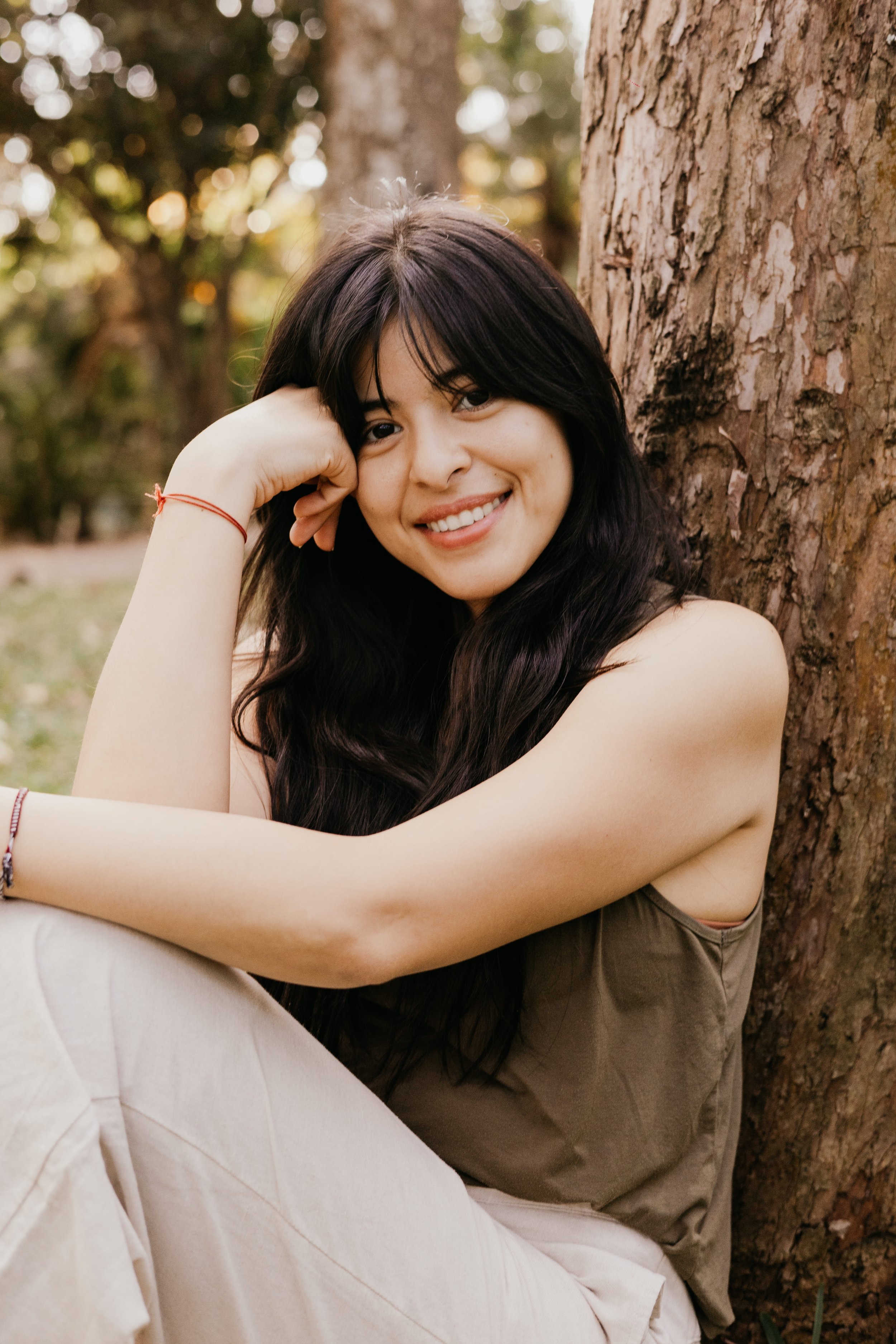 Ale la Doula sitting peacefully in nature, smiling at the camera to welcome families seeking maternal support in Montreal and Laval.