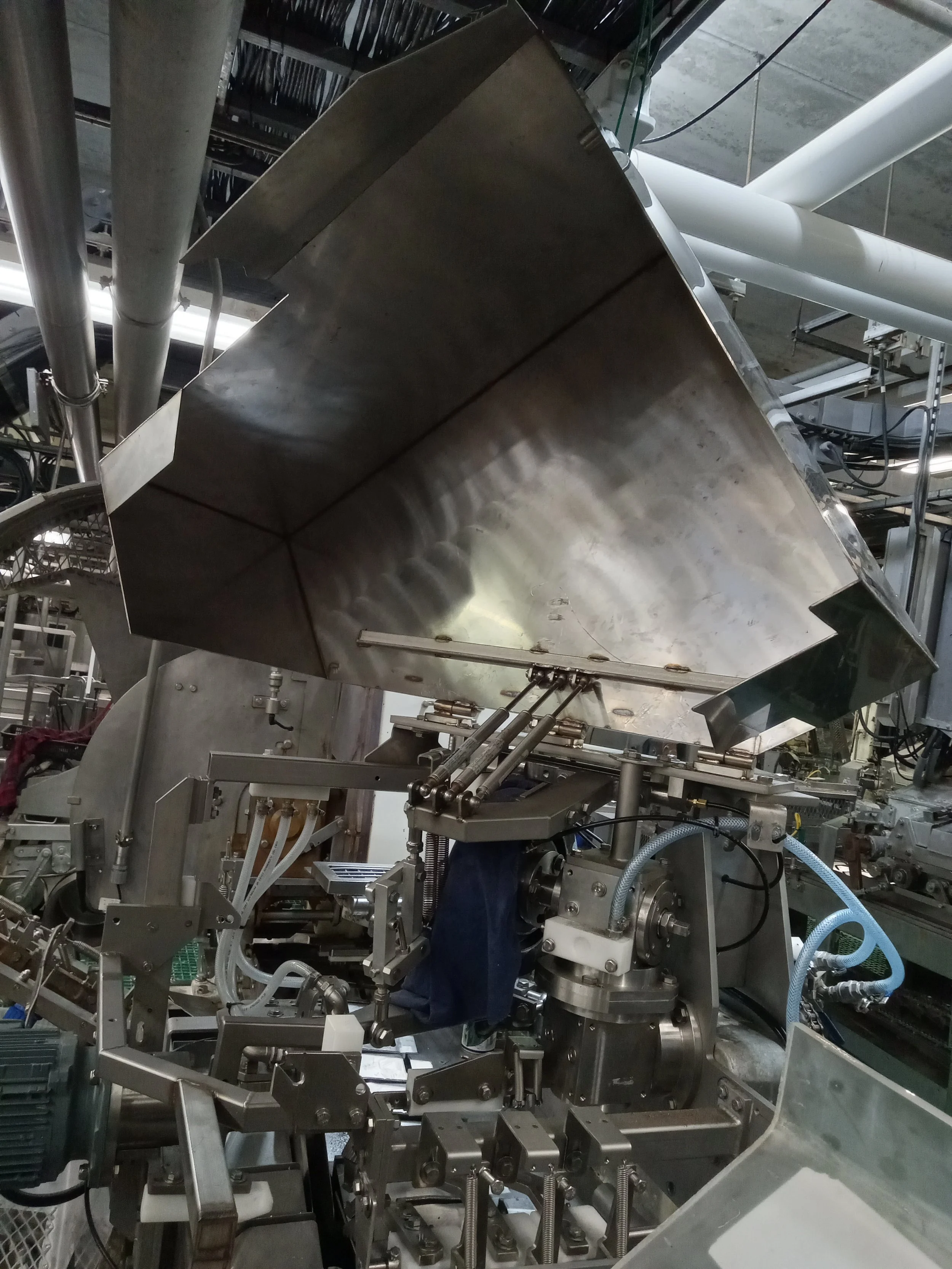 Industrial machinery with interconnected metal parts, pipes, and wires, inside a factory or processing plant.