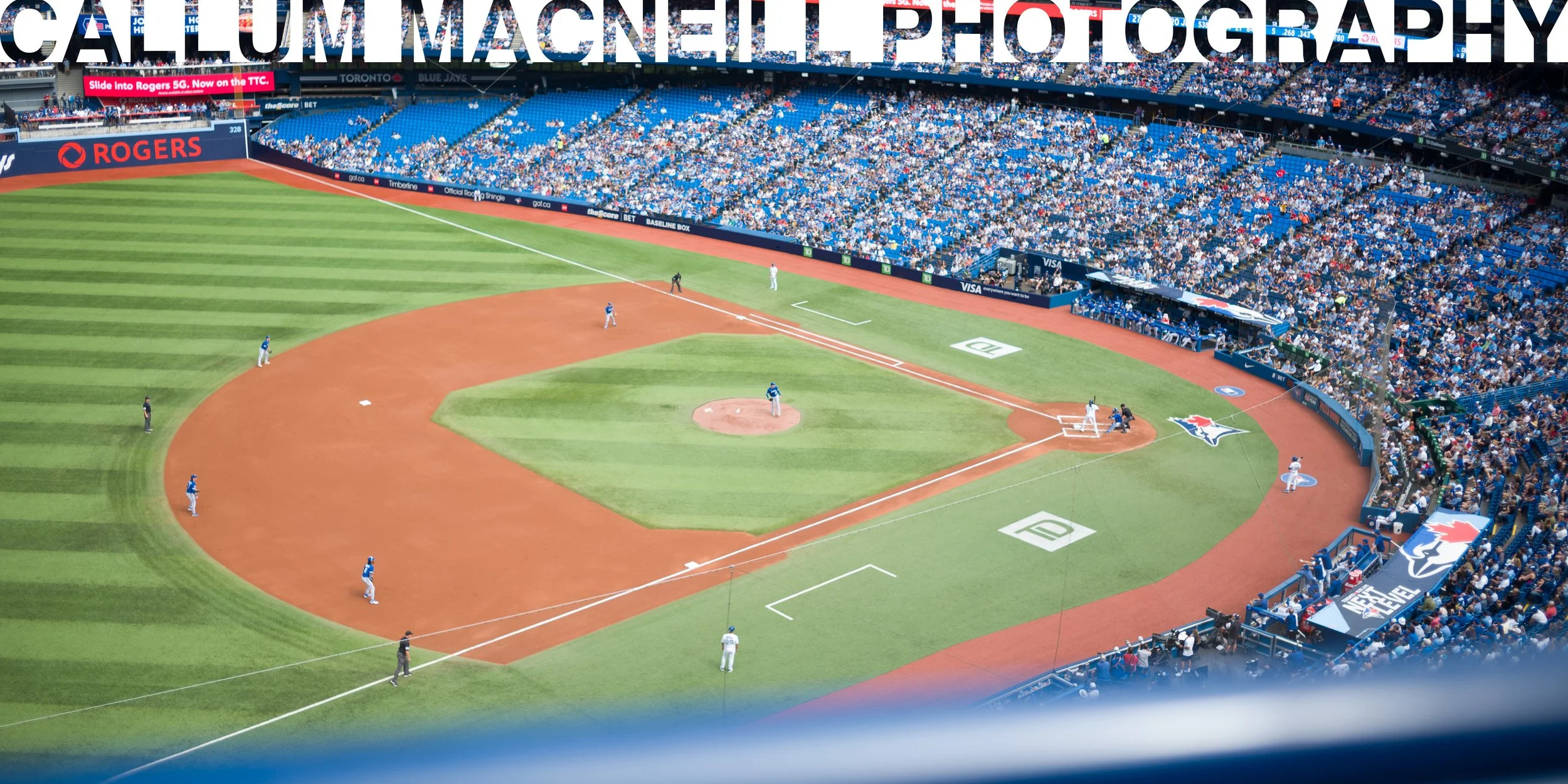 A baseball game in progress at a stadium filled with spectators, with players on the field preparing for a play.