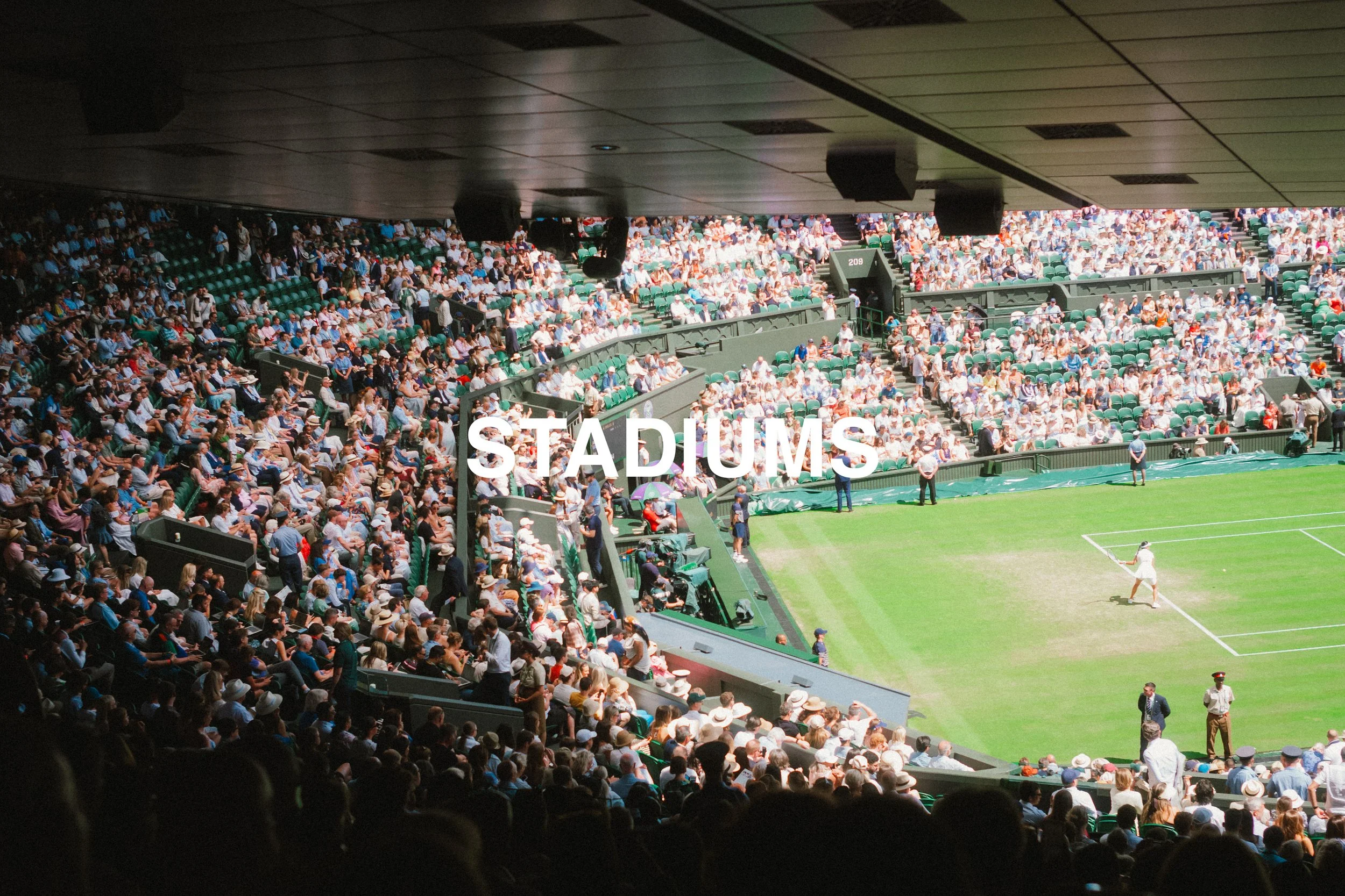 Crowd of spectators watching a tennis match at a stadium.