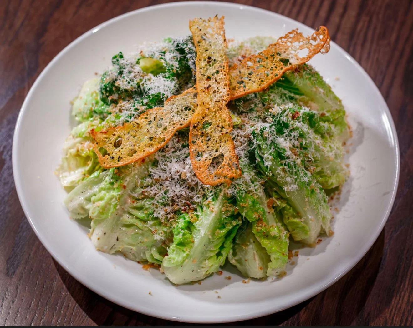 Caesar salad with romaine lettuce, grated cheese, toasted bread crumbs, and crispy Parmesan cheese crisps on top