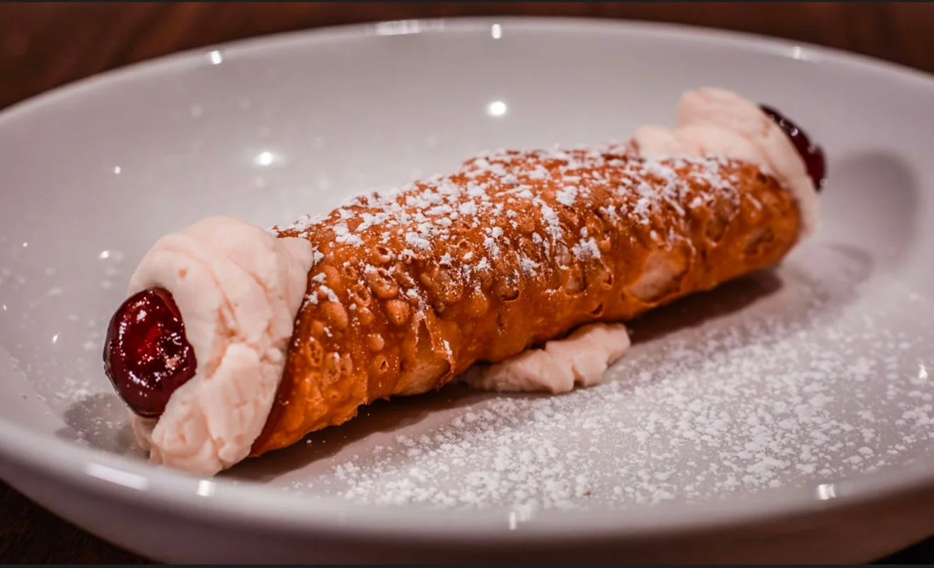 An ice cream cannoli with powdered sugar on a white plate