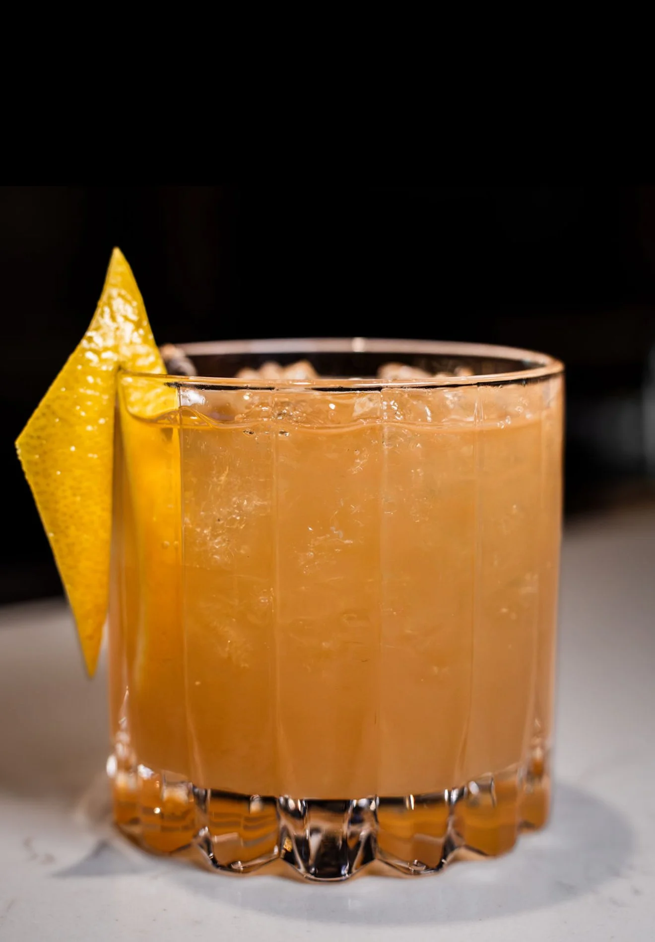 A glass of orange juice with a lemon wedge garnish.