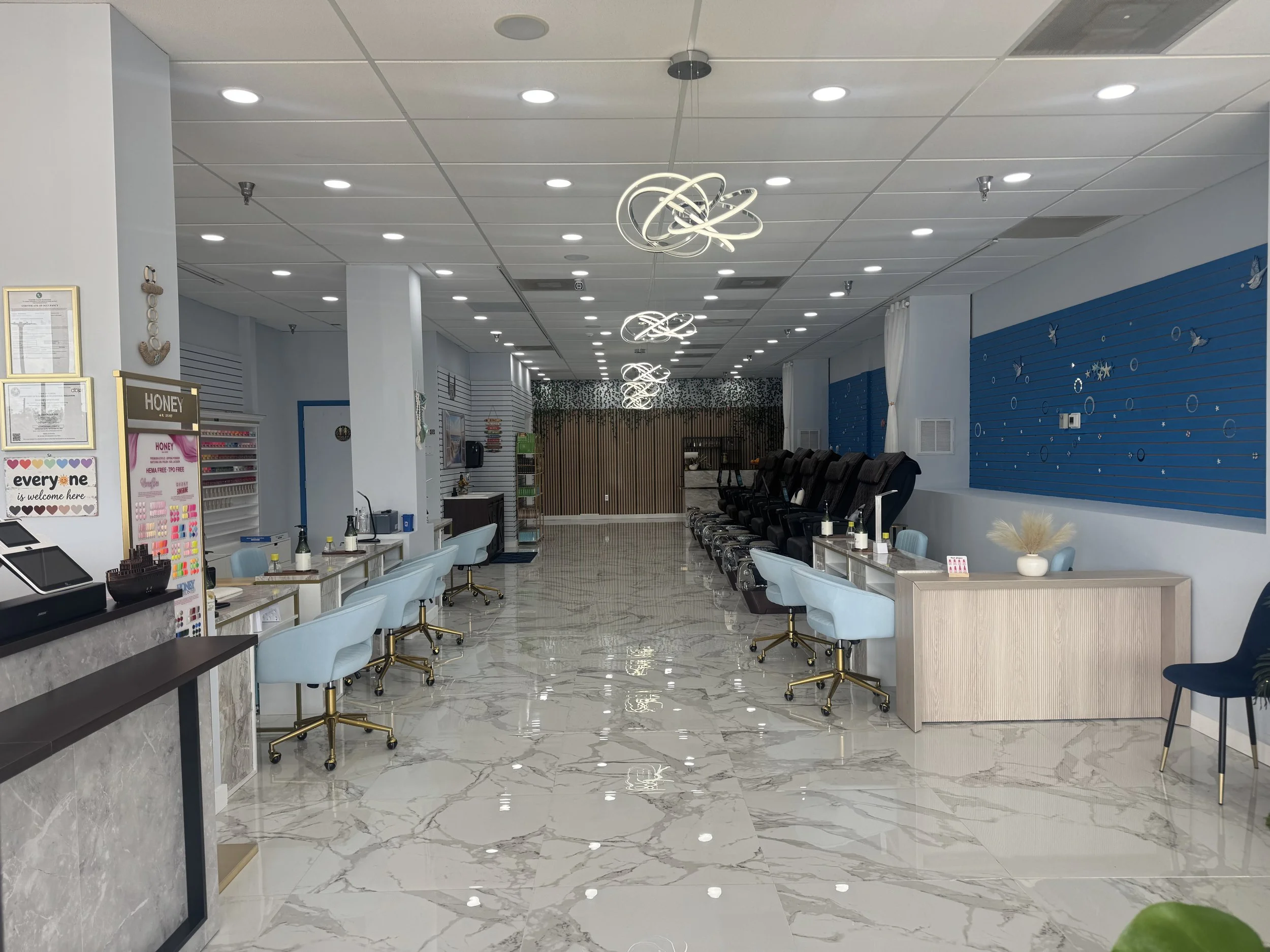 Empty spa or salon with chairs for pedicure or massage, decorative lighting fixtures, and a blue wall with butterfly and circle decorations.