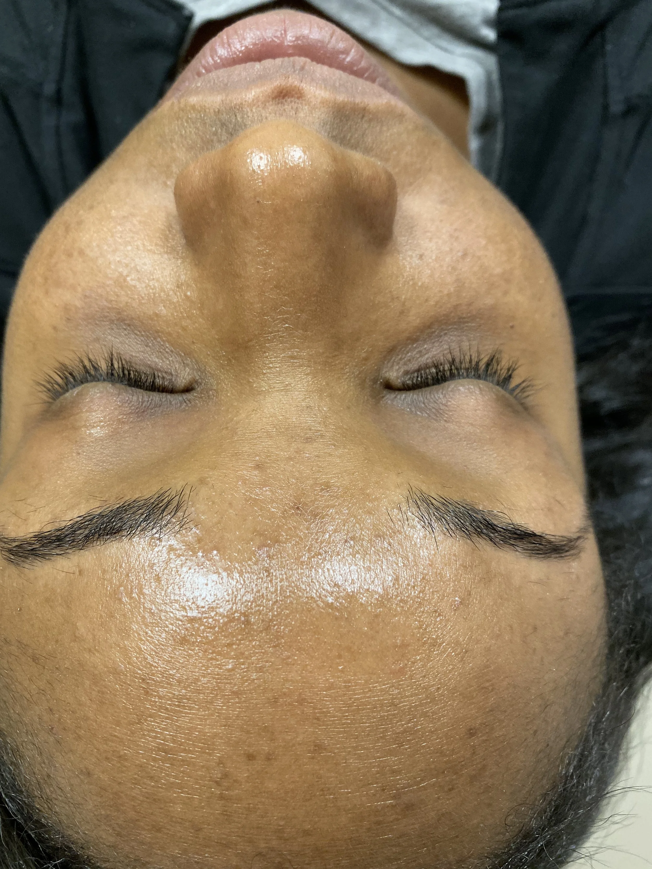 Close-up of a person's face with eyes closed, showing smooth skin and light brown complexion.